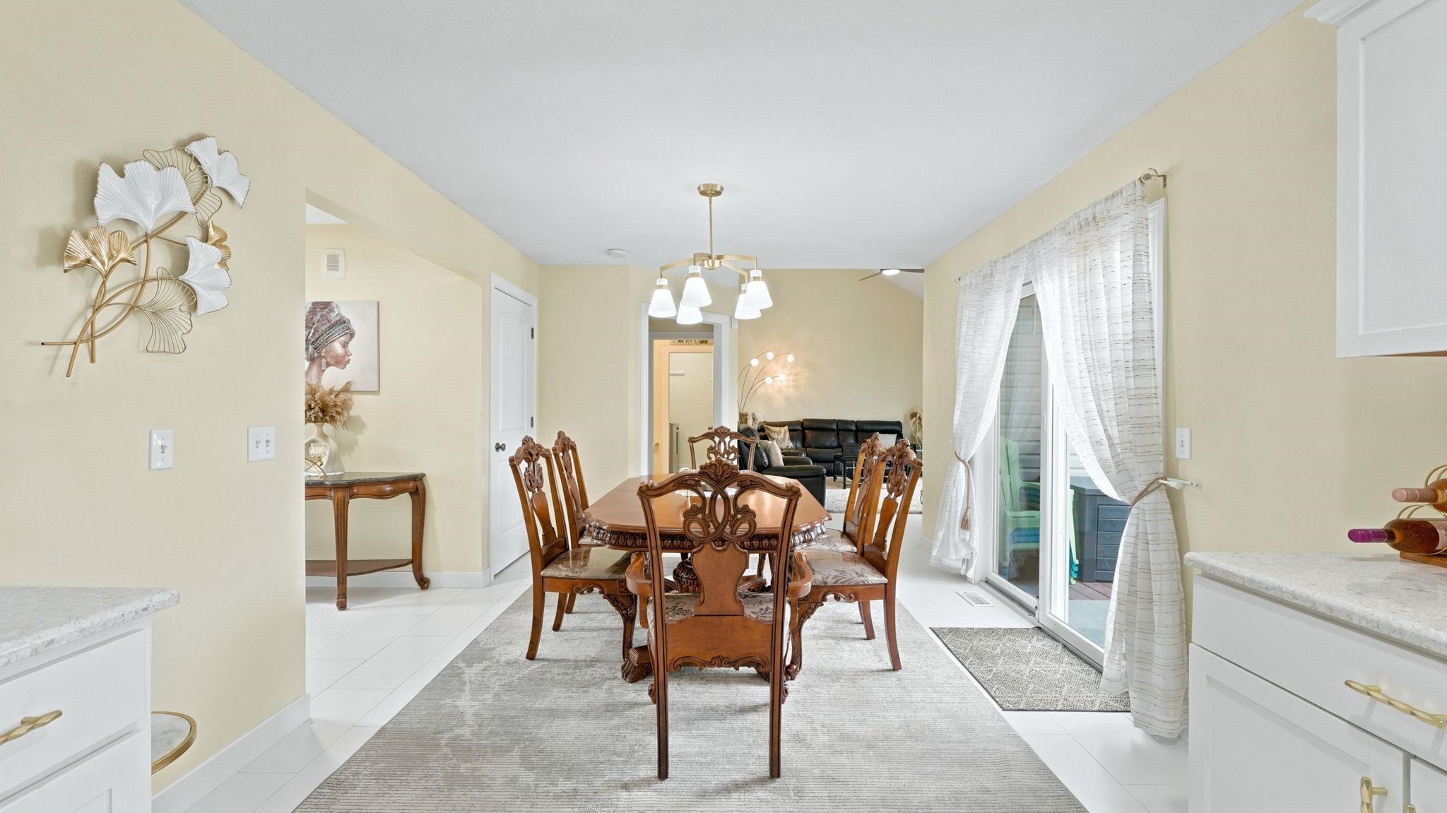 Spacious dining area featuring neutral wall tones, white tile flooring, and a sliding glass door for outdoor access