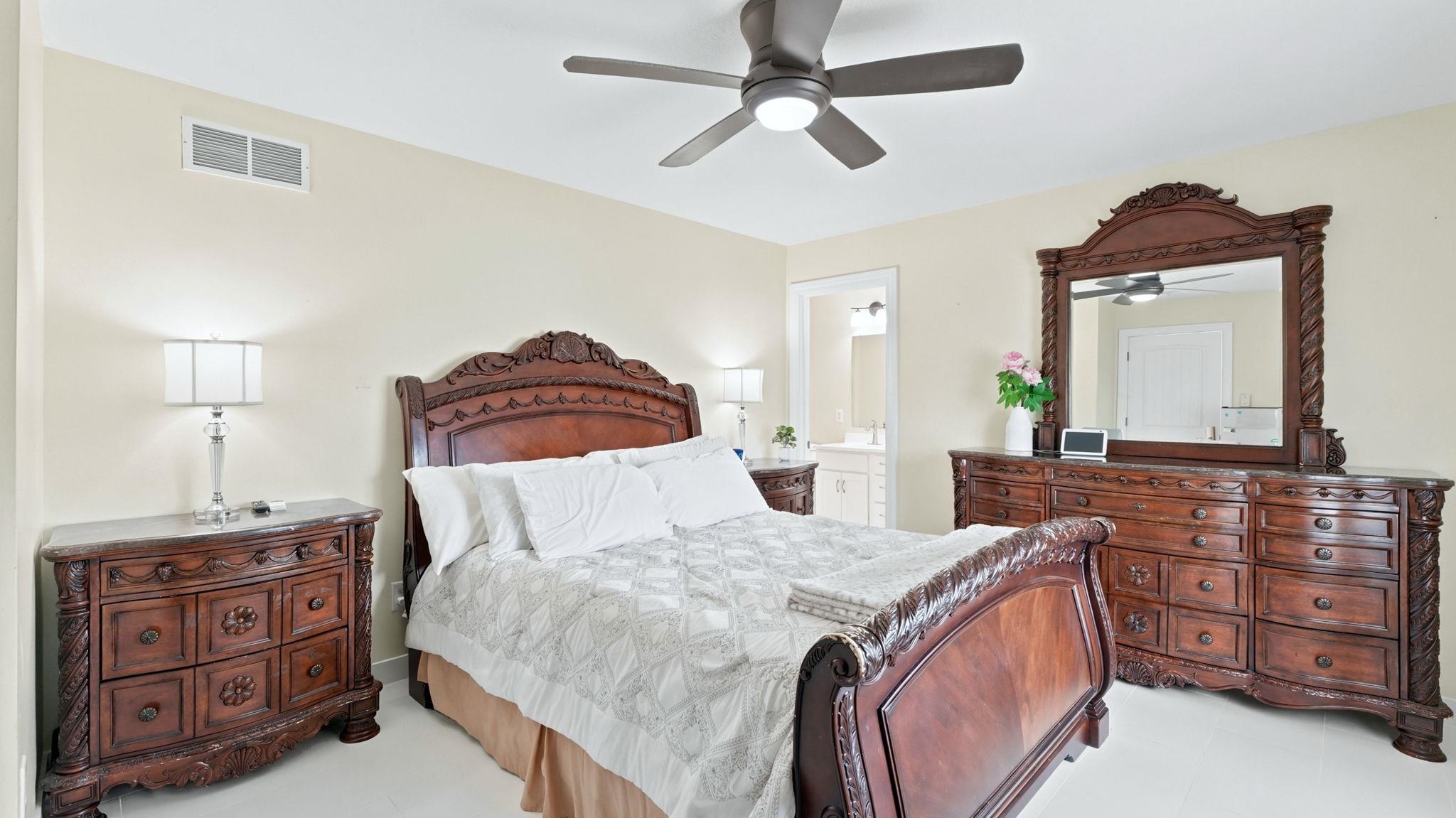 Spacious bedroom featuring light-toned walls and a ceiling fan with integrated lighting