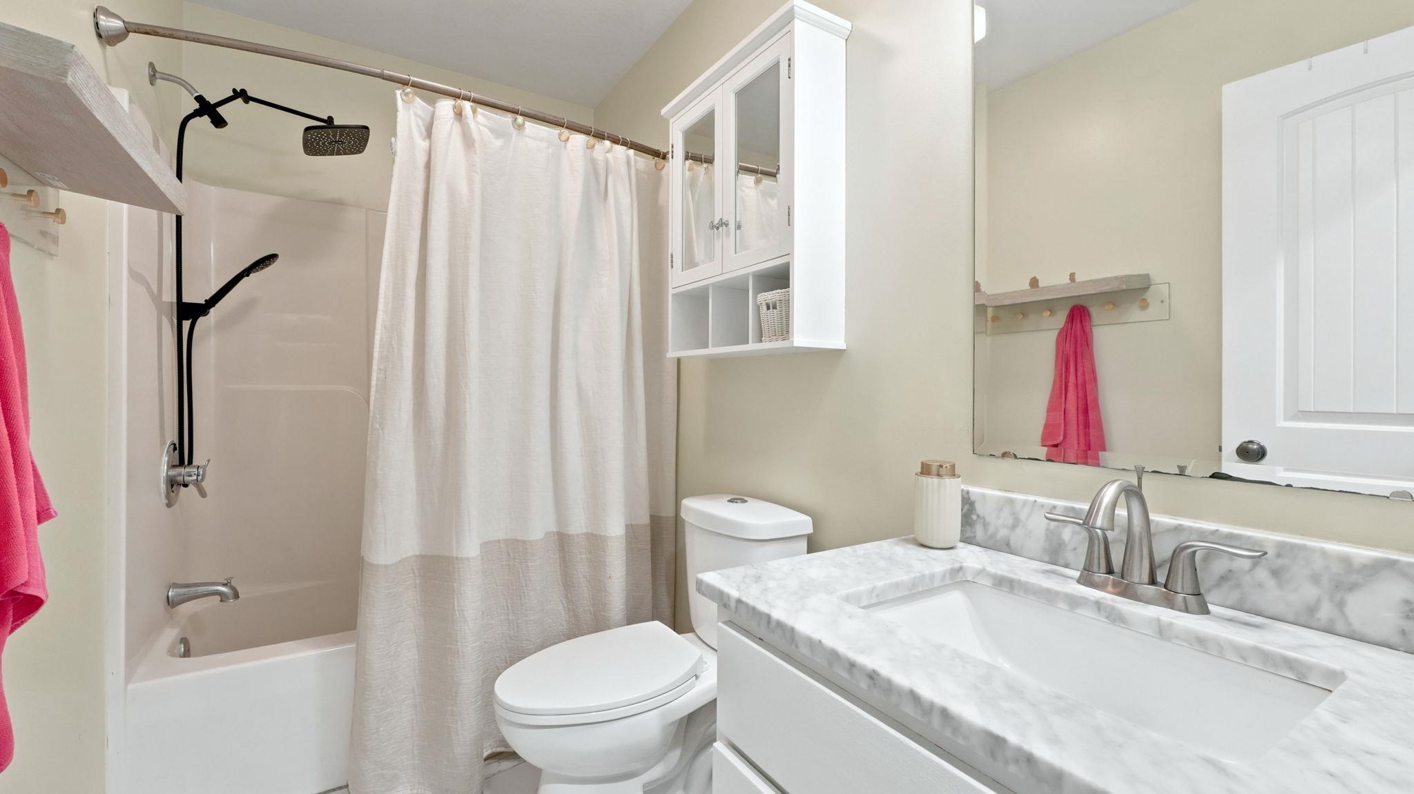 Bathroom featuring a white vanity with a rectangular undermount sink, a marble-patterned countertop, and a brushed nickel faucet