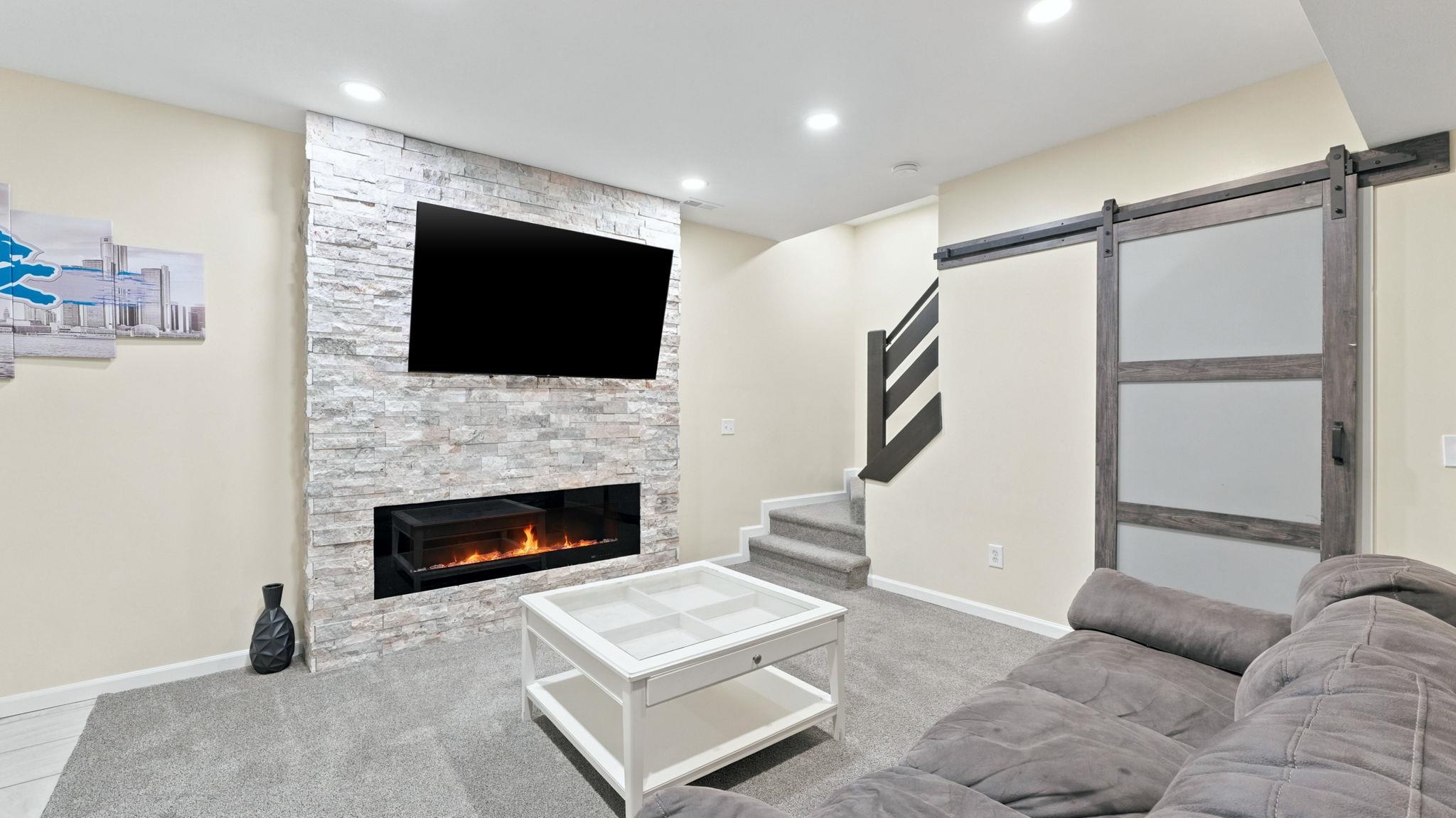 Living area featuring a floor-to-ceiling stone-faced accent wall with an integrated linear electric fireplace