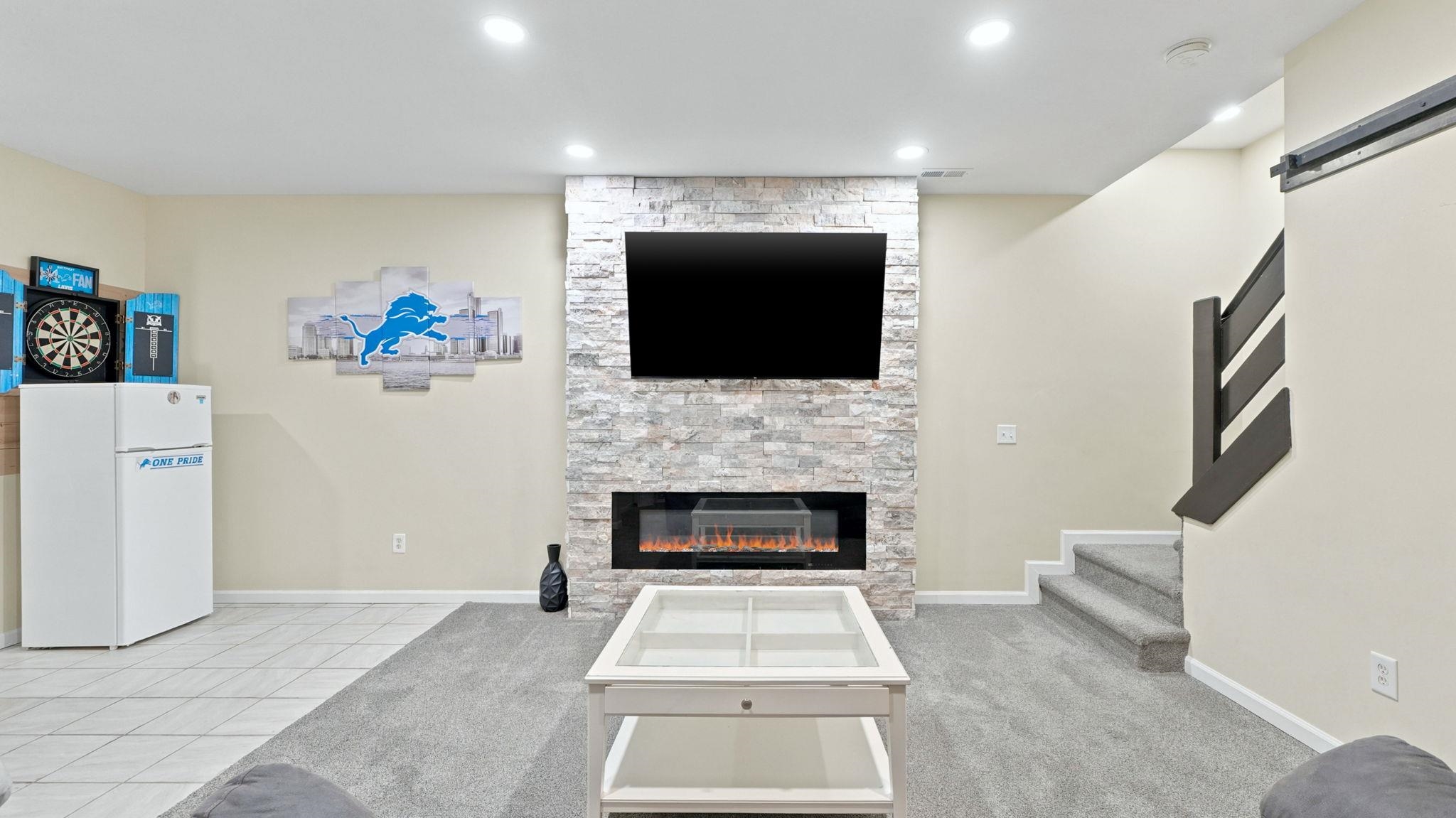 Living space featuring a stacked stone accent wall with a built-in electric fireplace and mounted television