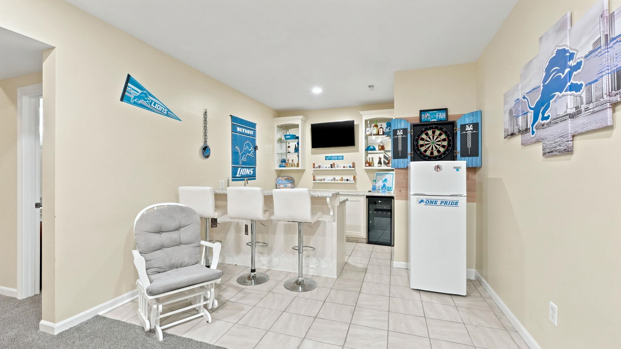 Entertainment area featuring a built-in bar with a stone-finish countertop, recessed lighting, and tile flooring