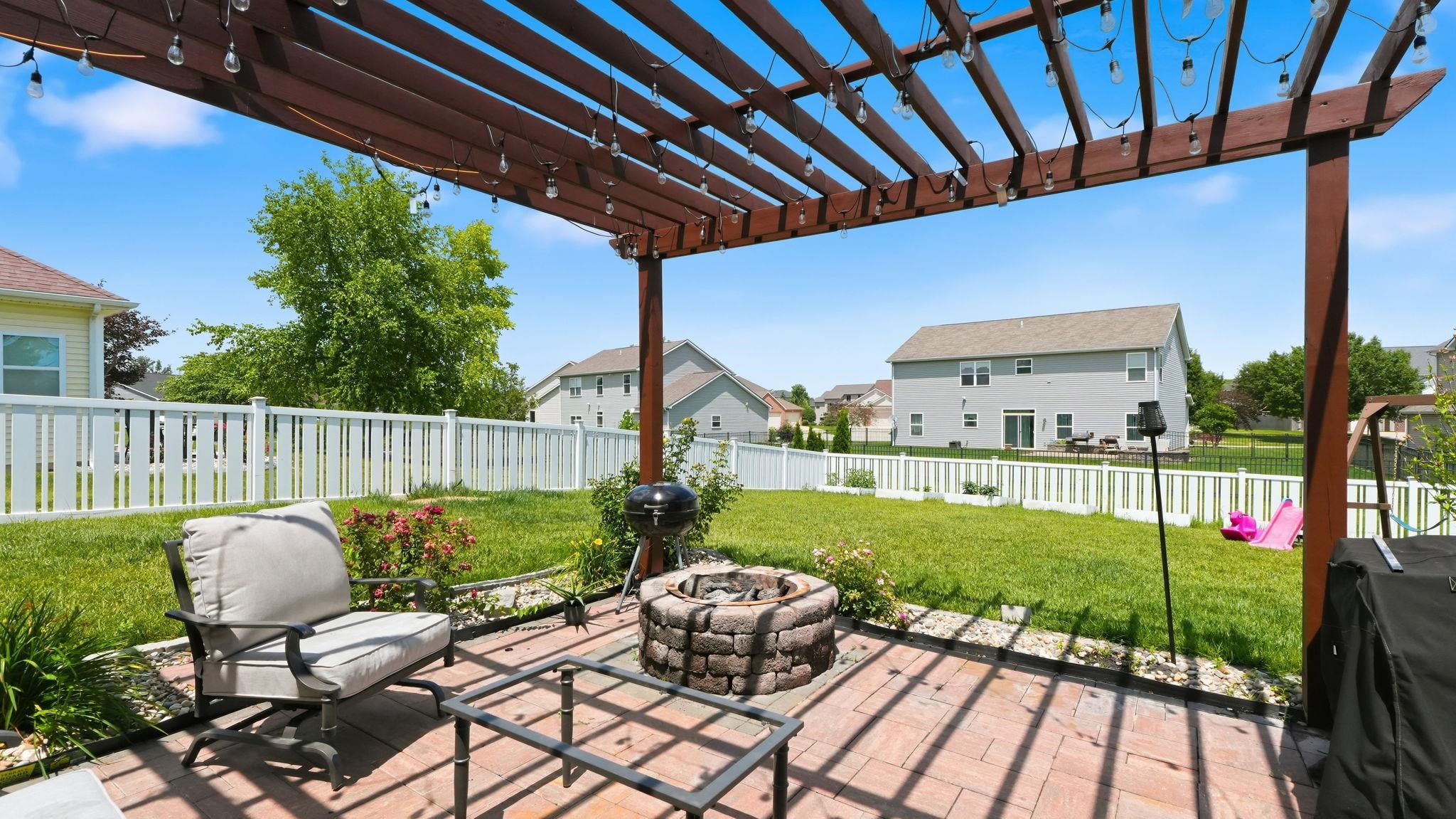 Expansive paver patio featuring a wood pergola with string lighting