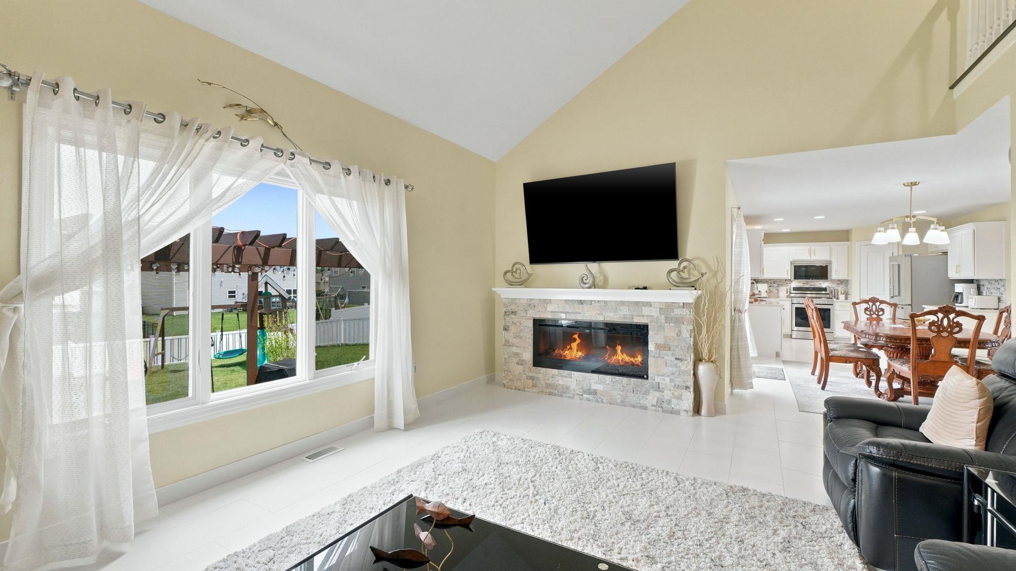 Living area featuring a vaulted ceiling and a stone-clad linear fireplace
