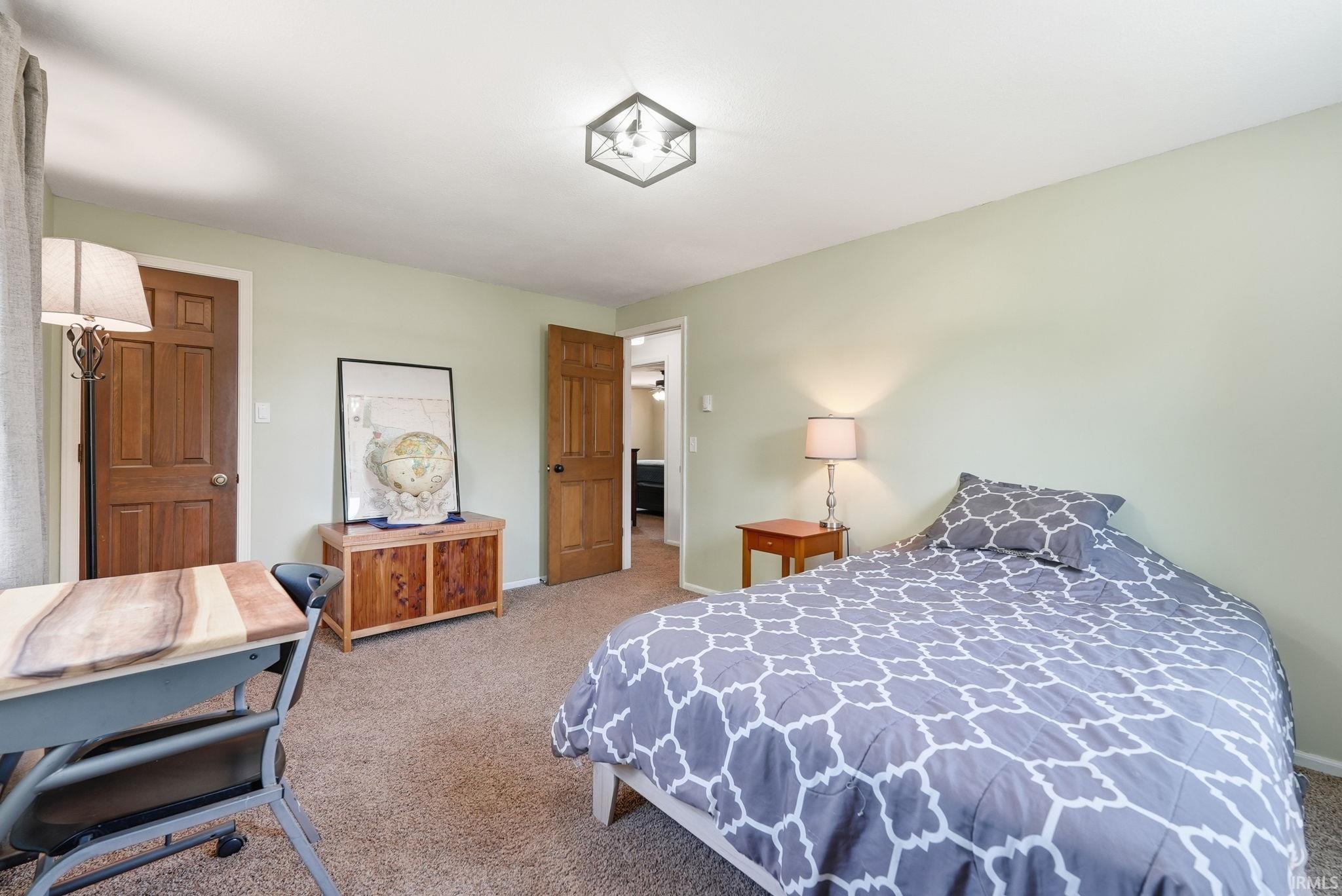 Bedroom featuring neutral carpeting, light green wall paint, and two paneled wood doors