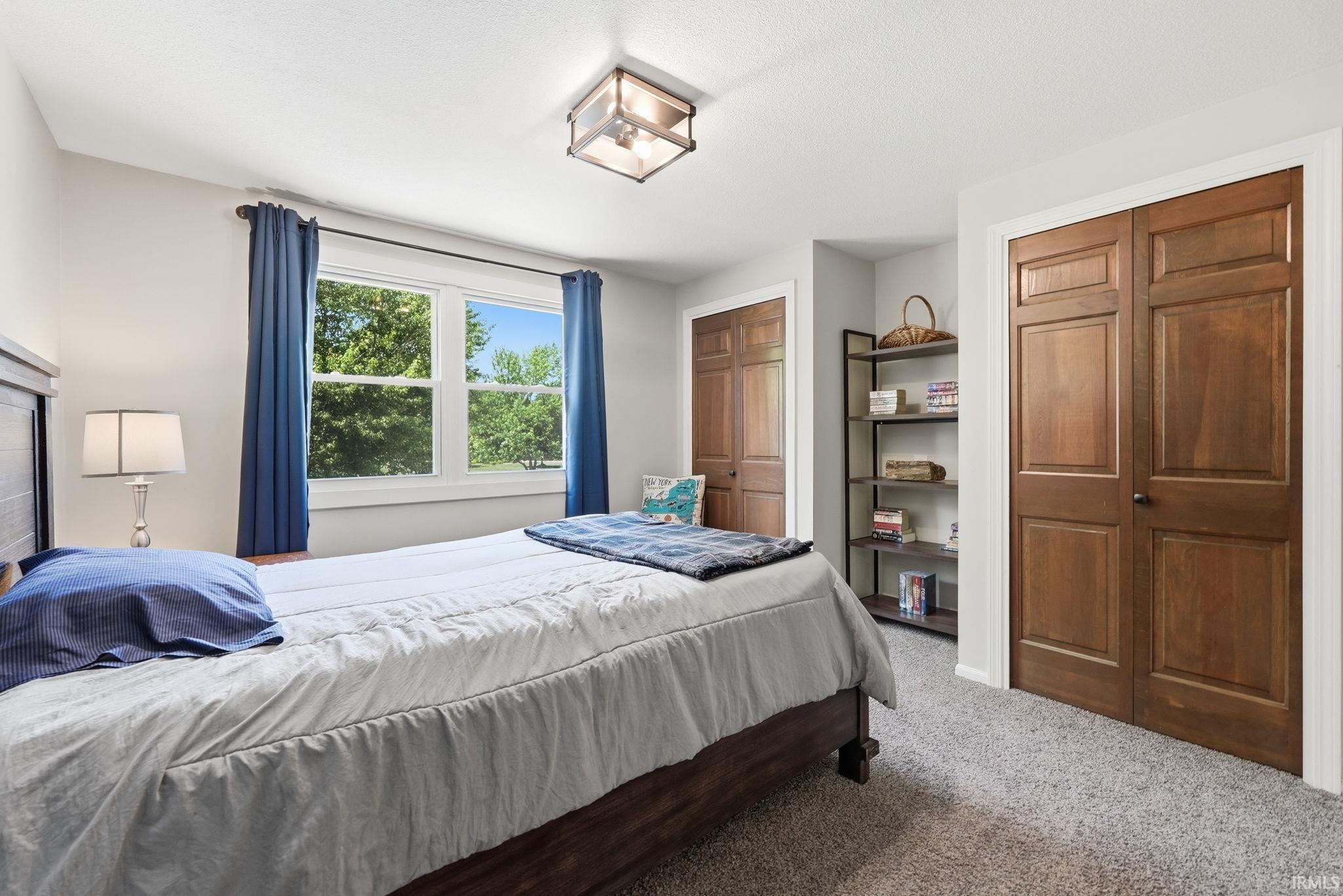 Carpeted room featuring a double window, wood-paneled bifold doors, and a built-in shelving unit