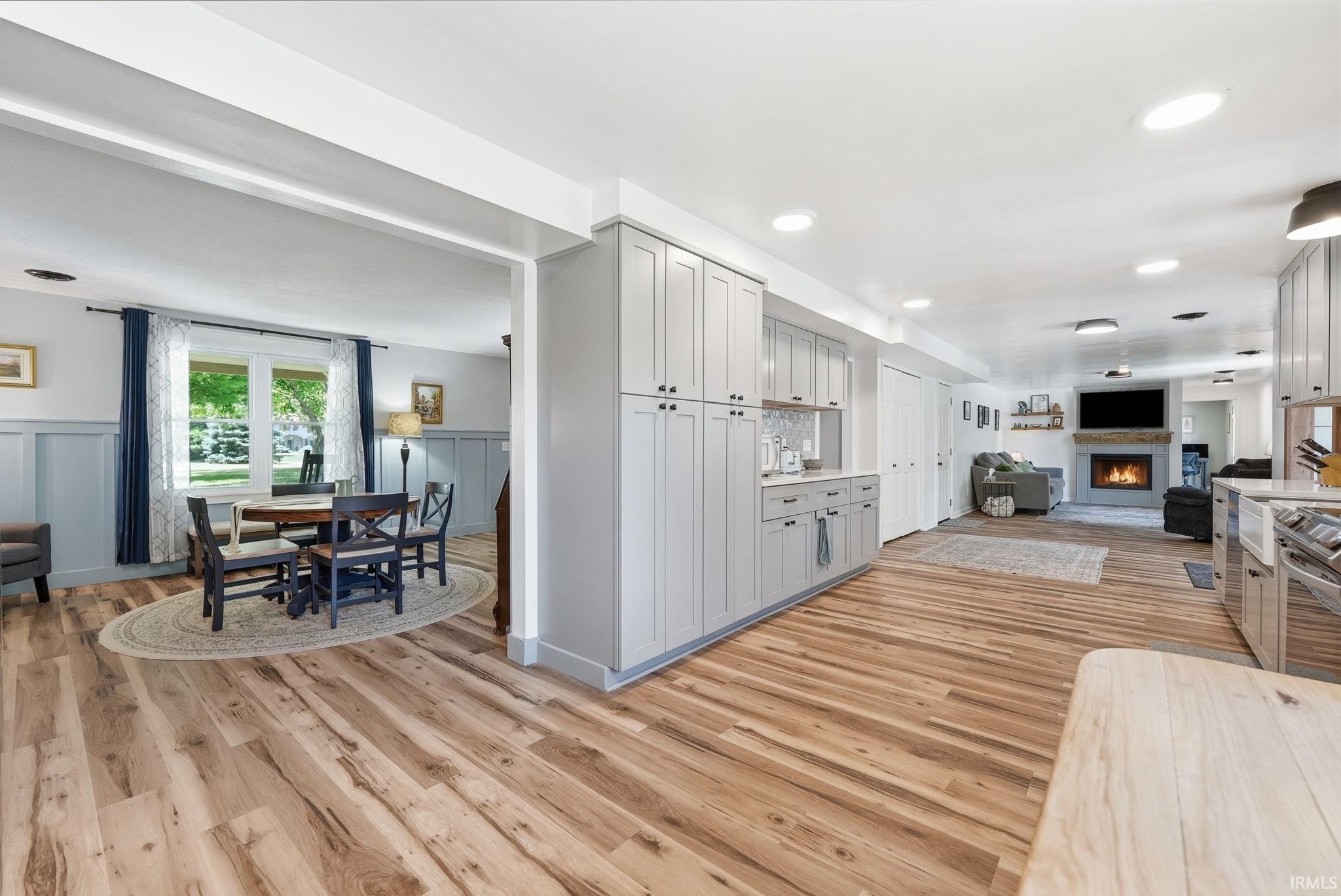Open-concept living space featuring wood-finish flooring, recessed lighting, and a stone-clad fireplace