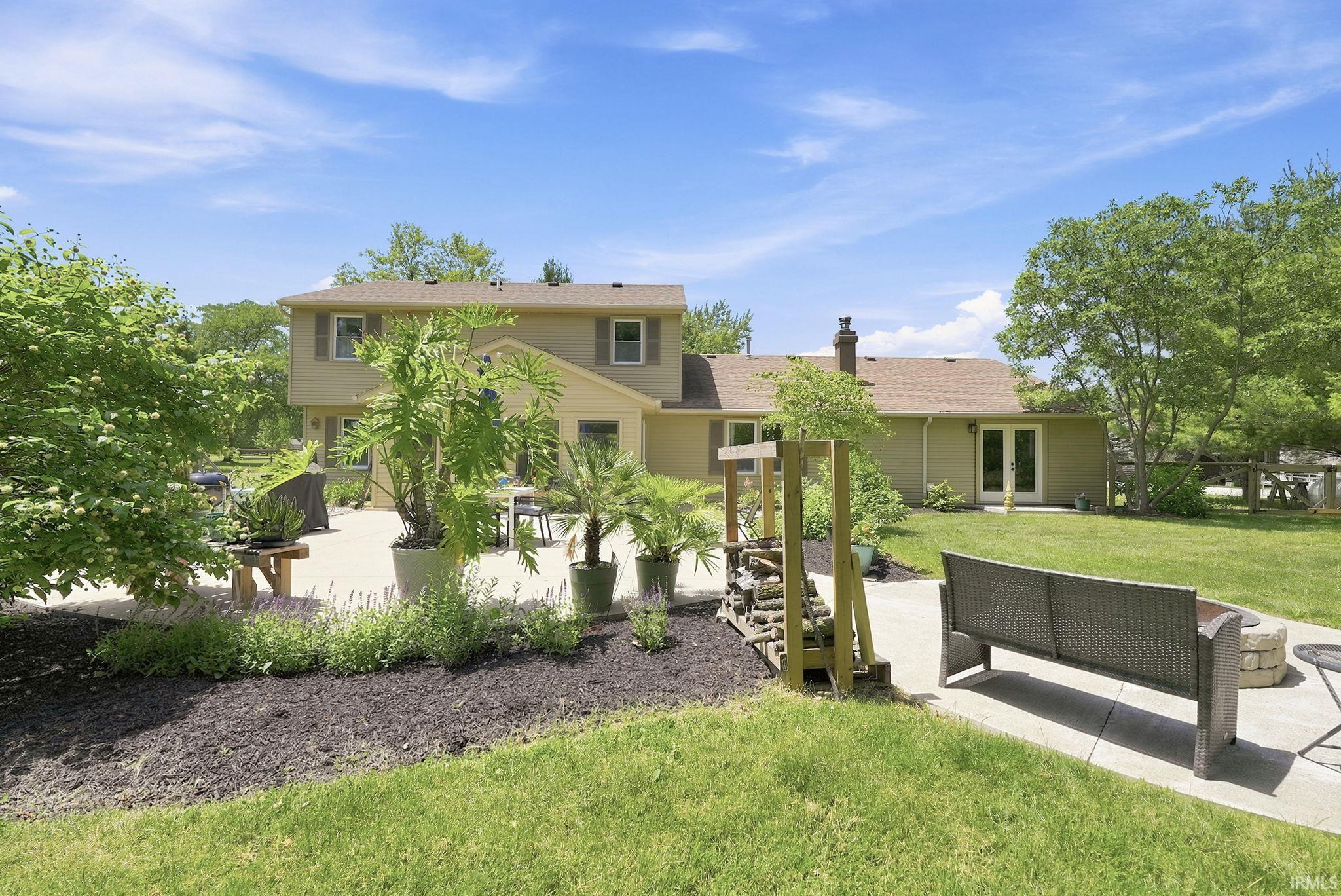 Expansive backyard featuring a large concrete patio, a stone fire pit, and a separate concrete path