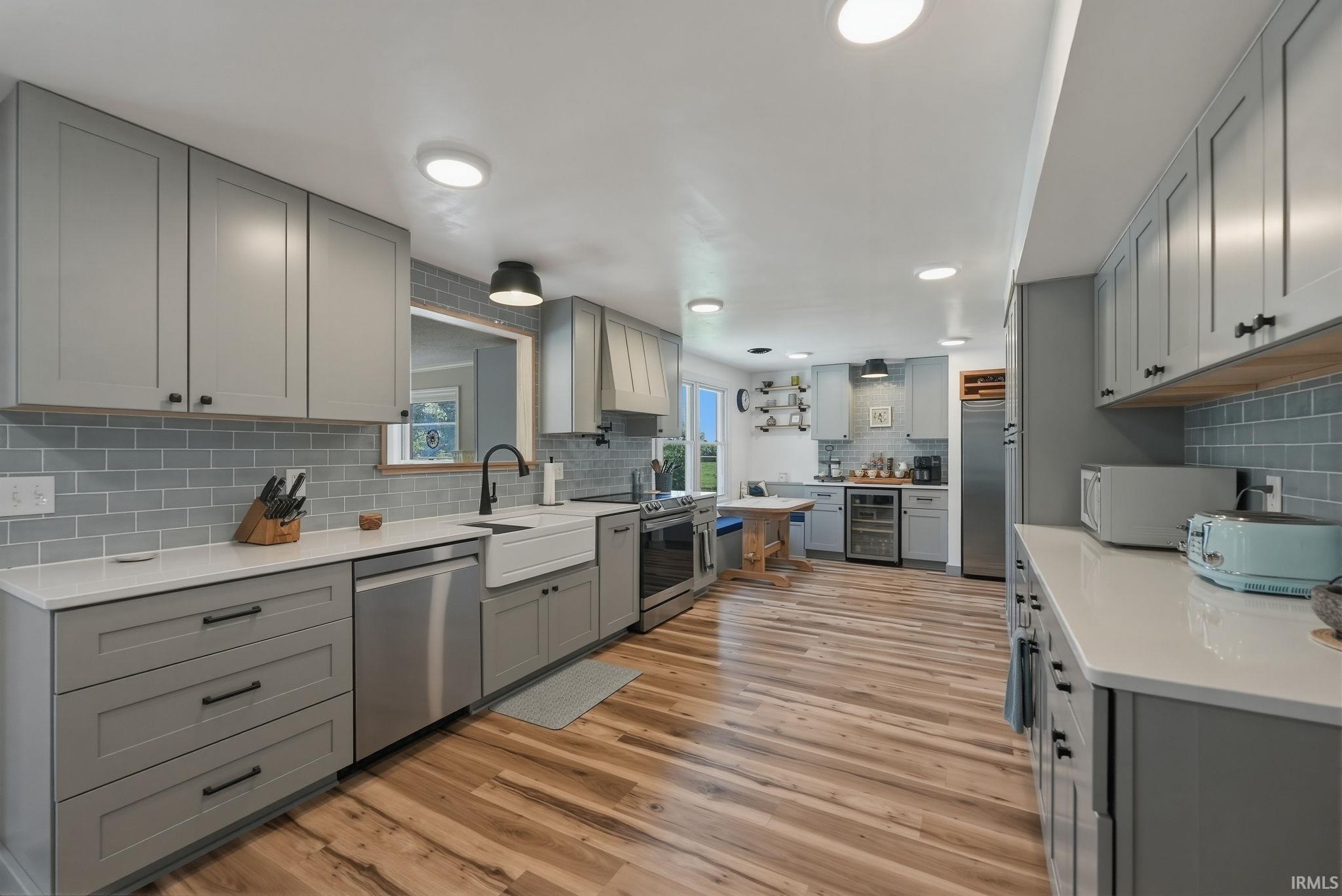 Spacious kitchen featuring light gray cabinetry with black hardware, white countertops, and a subway tile backsplash