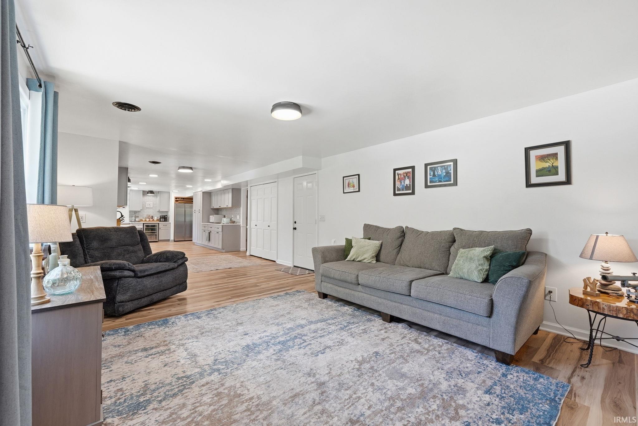 Open-concept living area featuring light wood-finish flooring, white walls, and recessed lighting