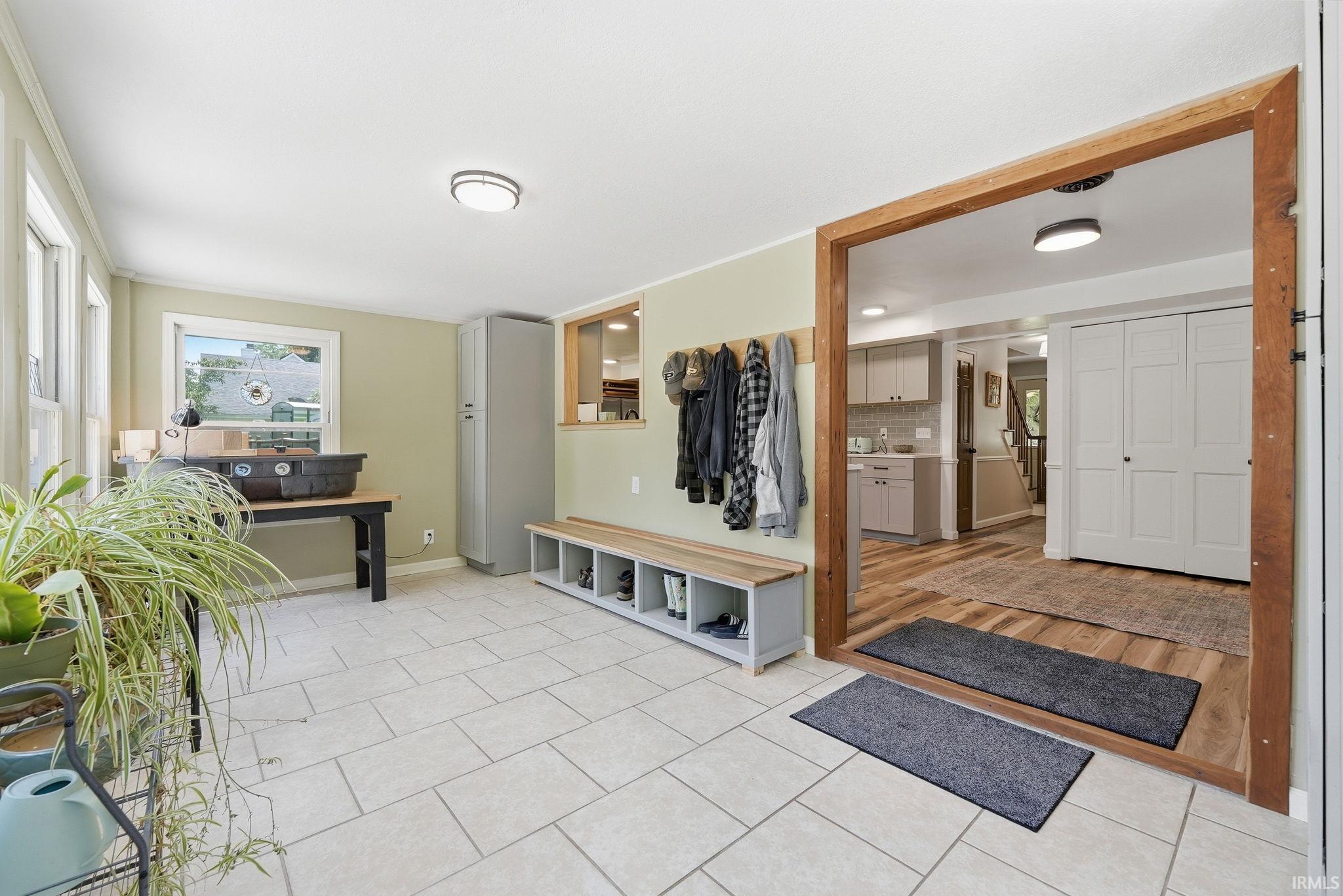 Bright sunroom featuring light-toned tile flooring, multiple windows, and a built-in storage bench