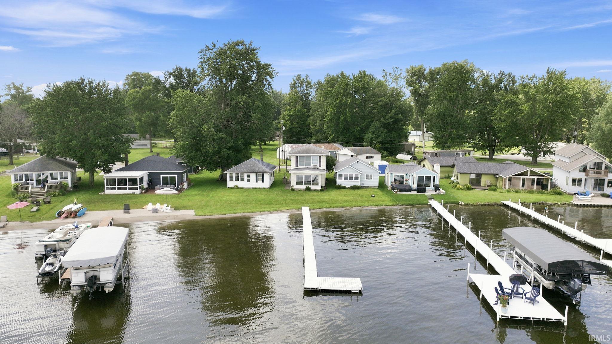 Expansive waterfront property featuring multiple private docks, sandy beach access, and mature trees