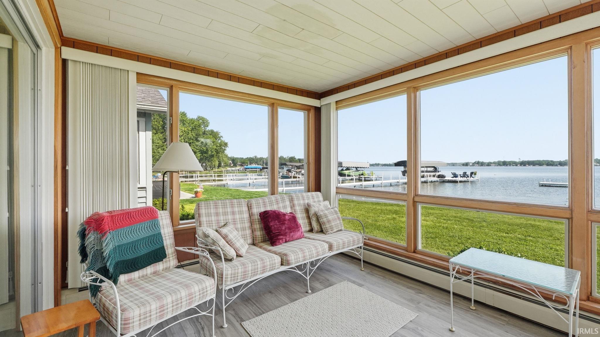 Sunroom featuring expansive waterfront views and wood-finish flooring