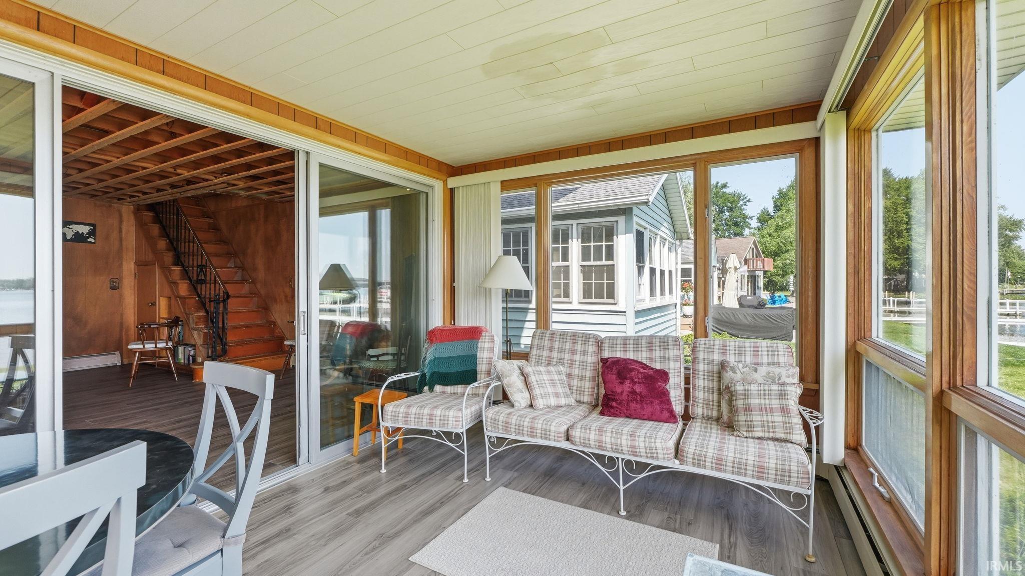 Enclosed sunroom featuring wood-finish flooring, white panel ceiling, extensive windowing, and sliding glass doors