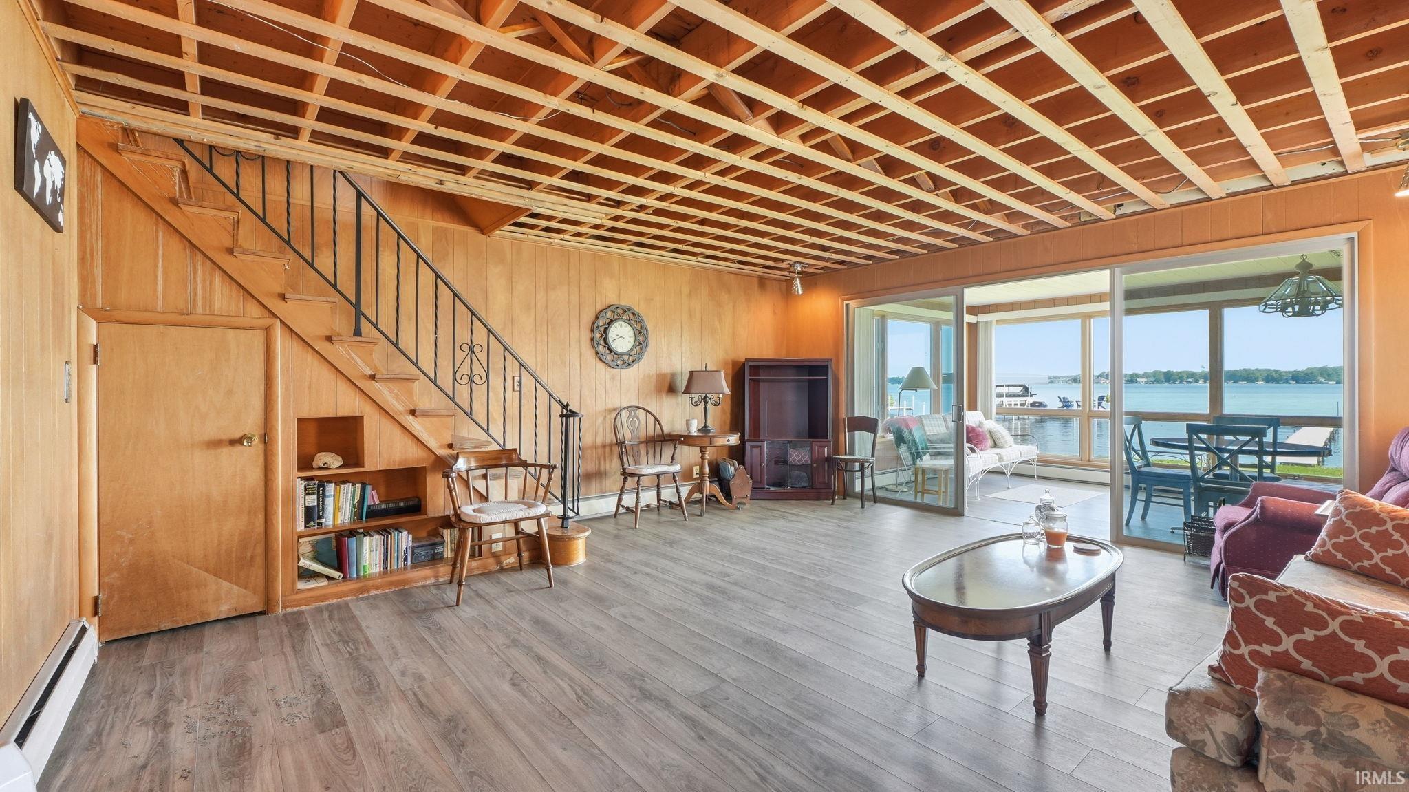 Expansive room featuring wood-finish flooring, wood paneling, and an exposed wood beam ceiling