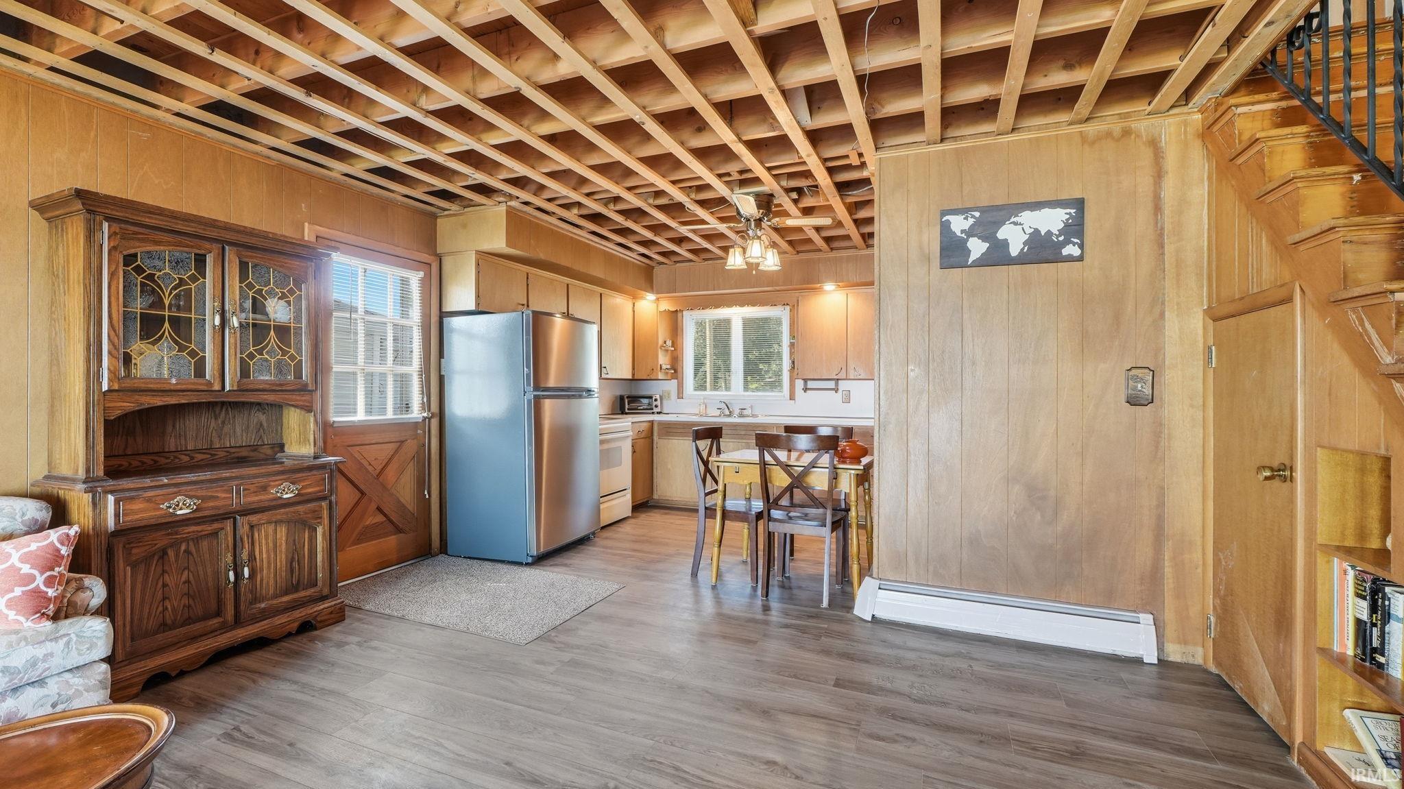 Open concept living area featuring wood-finish flooring, exposed wood ceiling joists, and paneled walls