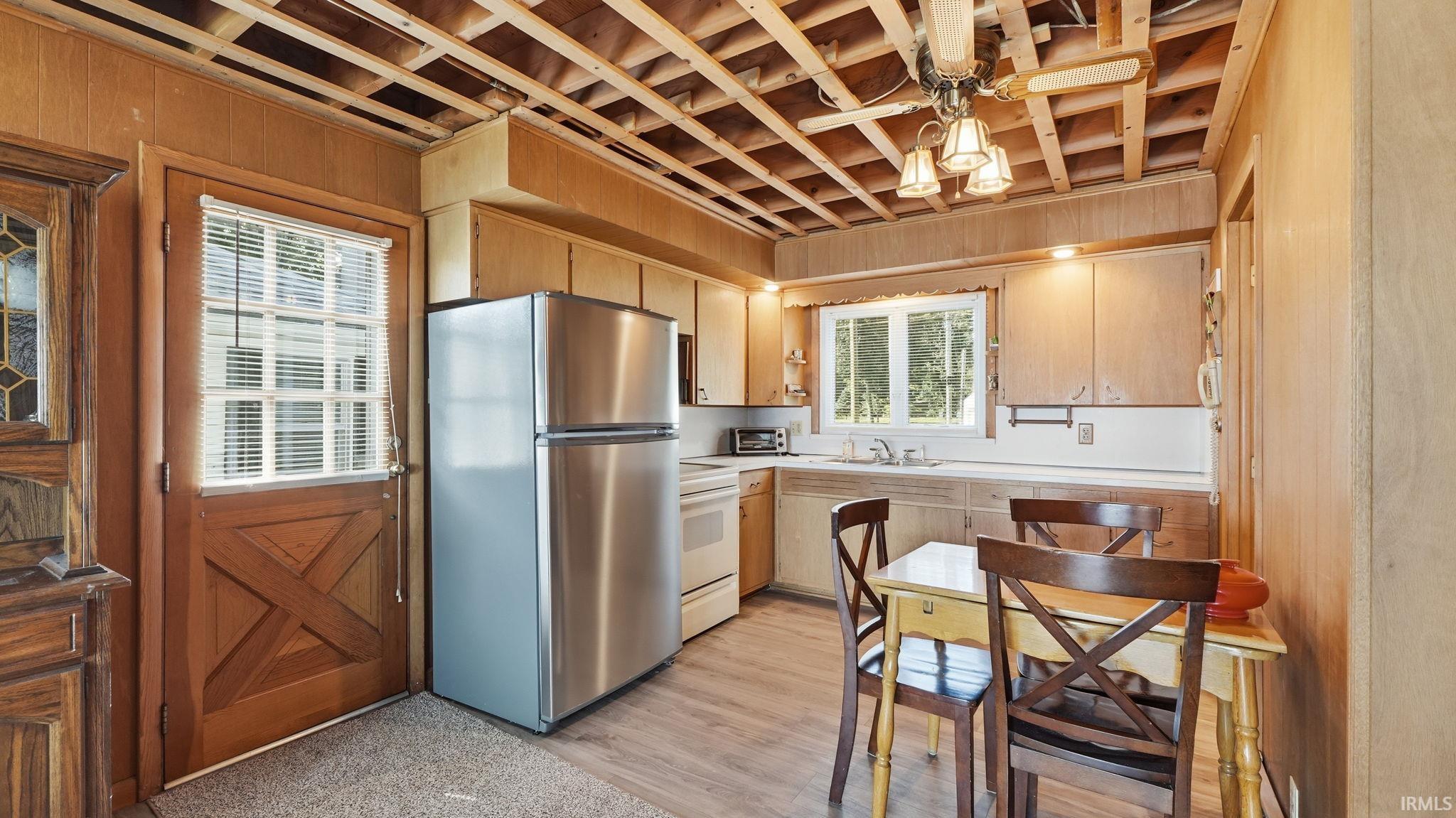 Kitchen featuring wood-finish paneling, stainless steel refrigerator, wood-finish flooring, and a dutch door with window