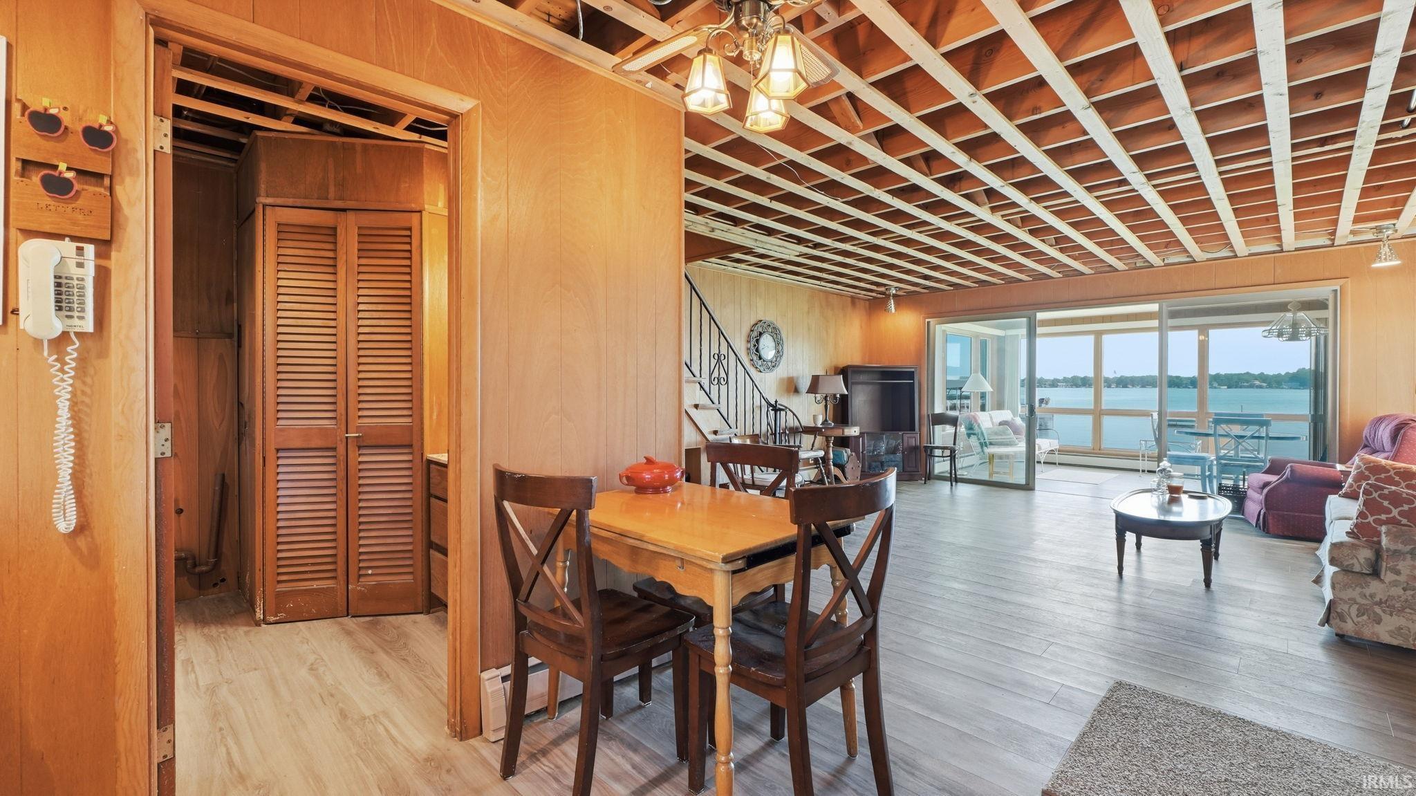 Open living area featuring wood-finish flooring, exposed ceiling joists, and a full wall of sliding glass doors