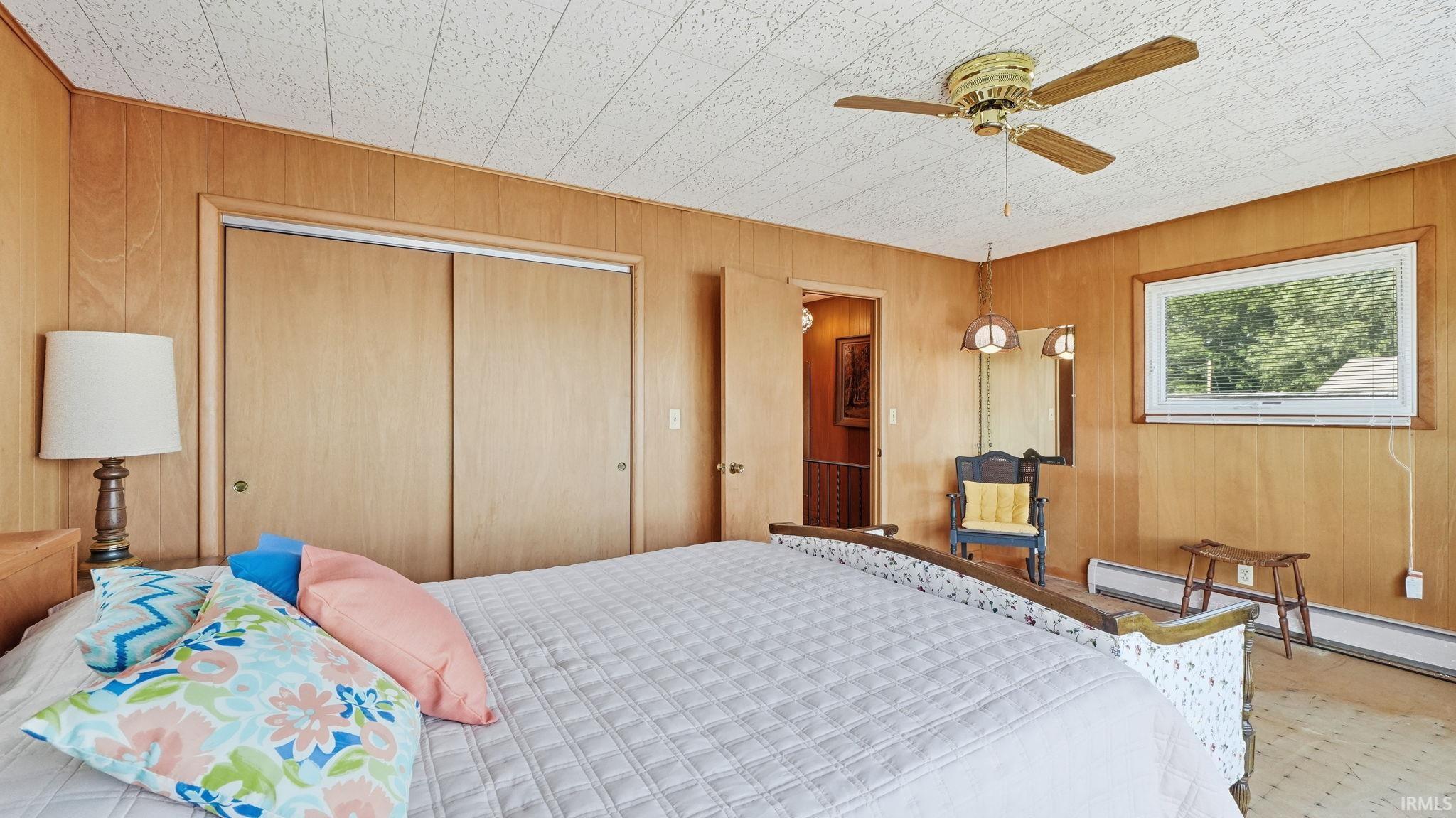 Bedroom featuring wood-panel walls and a textured ceiling
