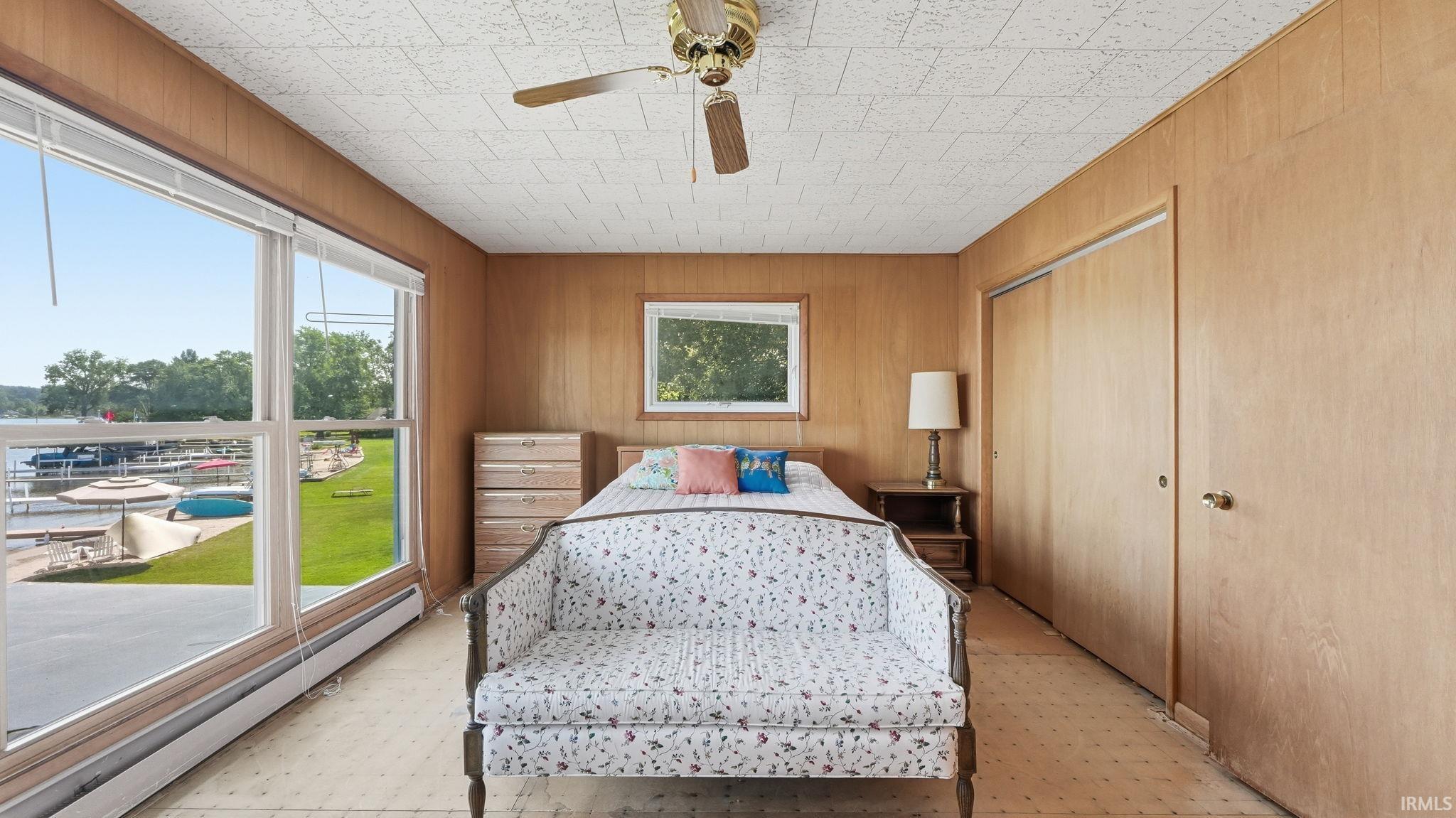 Room with wood-panel walls featuring a large picture window overlooking a body of water