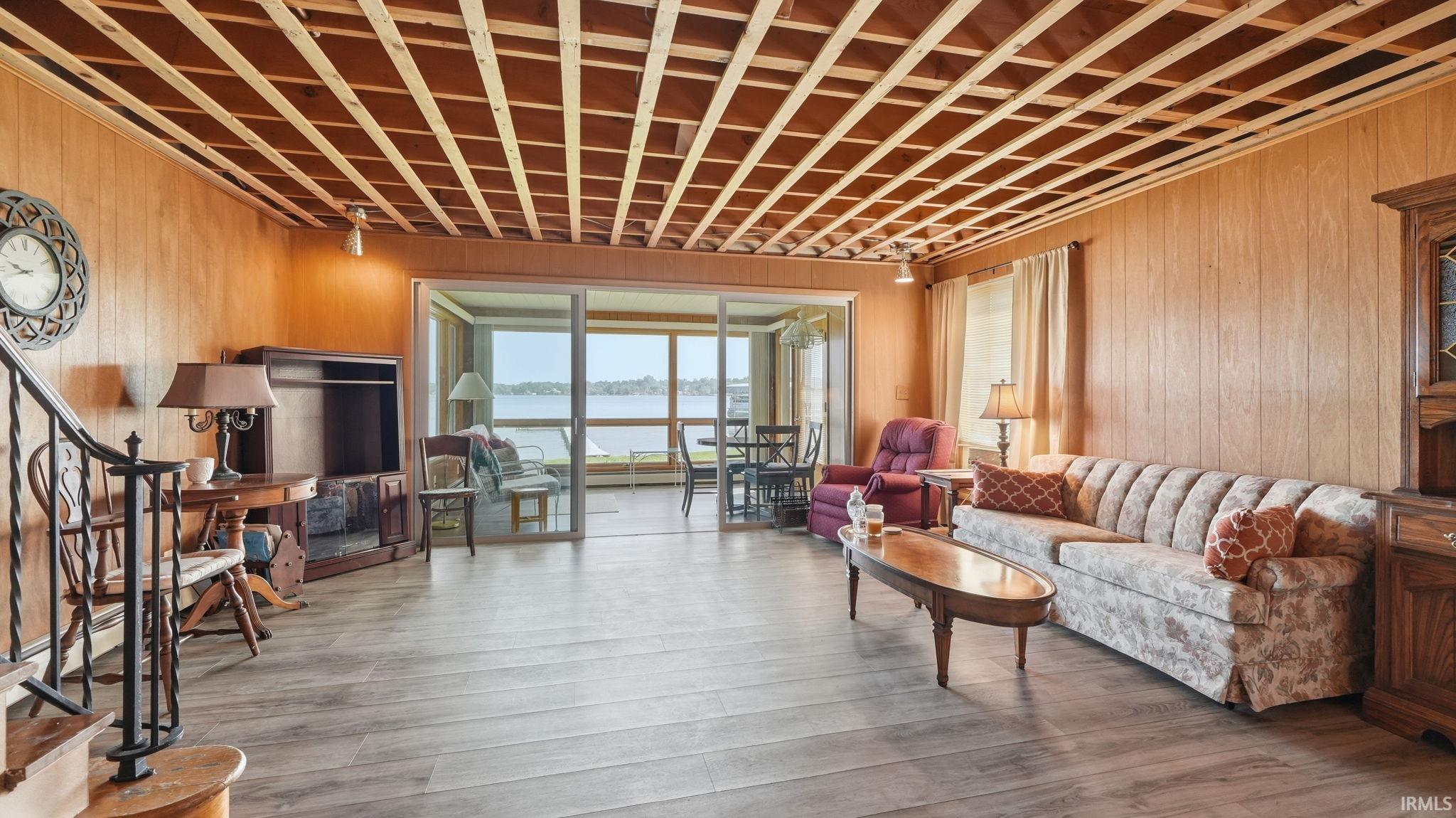 Spacious room featuring wood-finish flooring, wood paneling, and an exposed ceiling grid