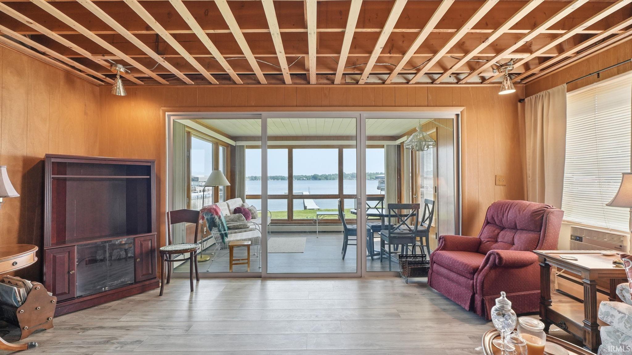 Sliding glass doors open to an enclosed sunroom with panoramic water scenery