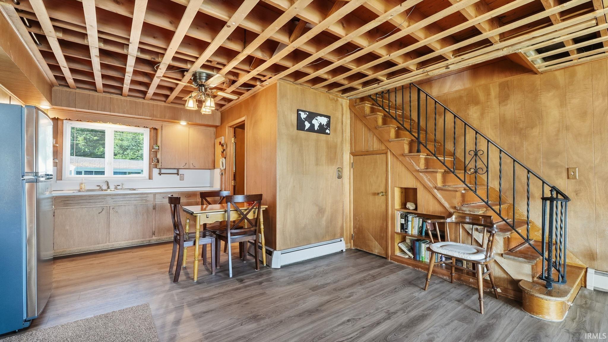 Open-concept kitchen and living area featuring wood-finish flooring and wood-paneled walls