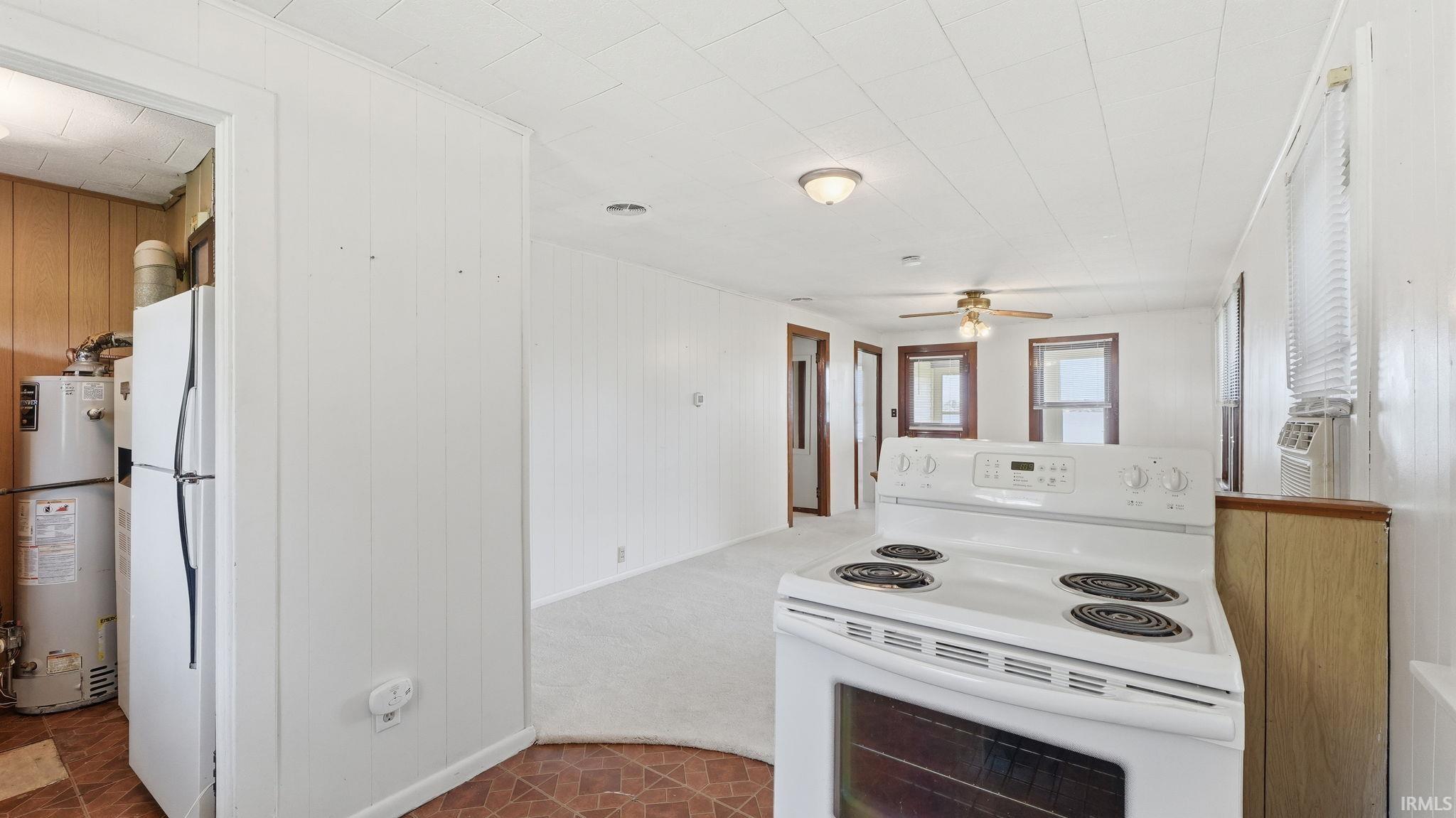 Kitchen area with a white electric range, wood-finish paneling, and a vinyl tile floor