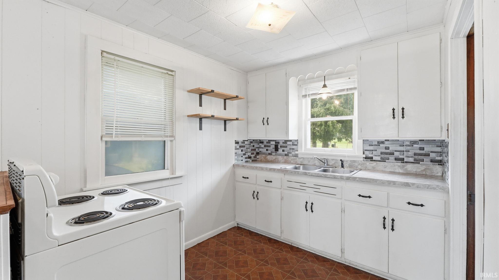 Kitchen featuring white cabinetry with dark hardware, a mosaic tile backsplash, a double basin sink, and a built-in range