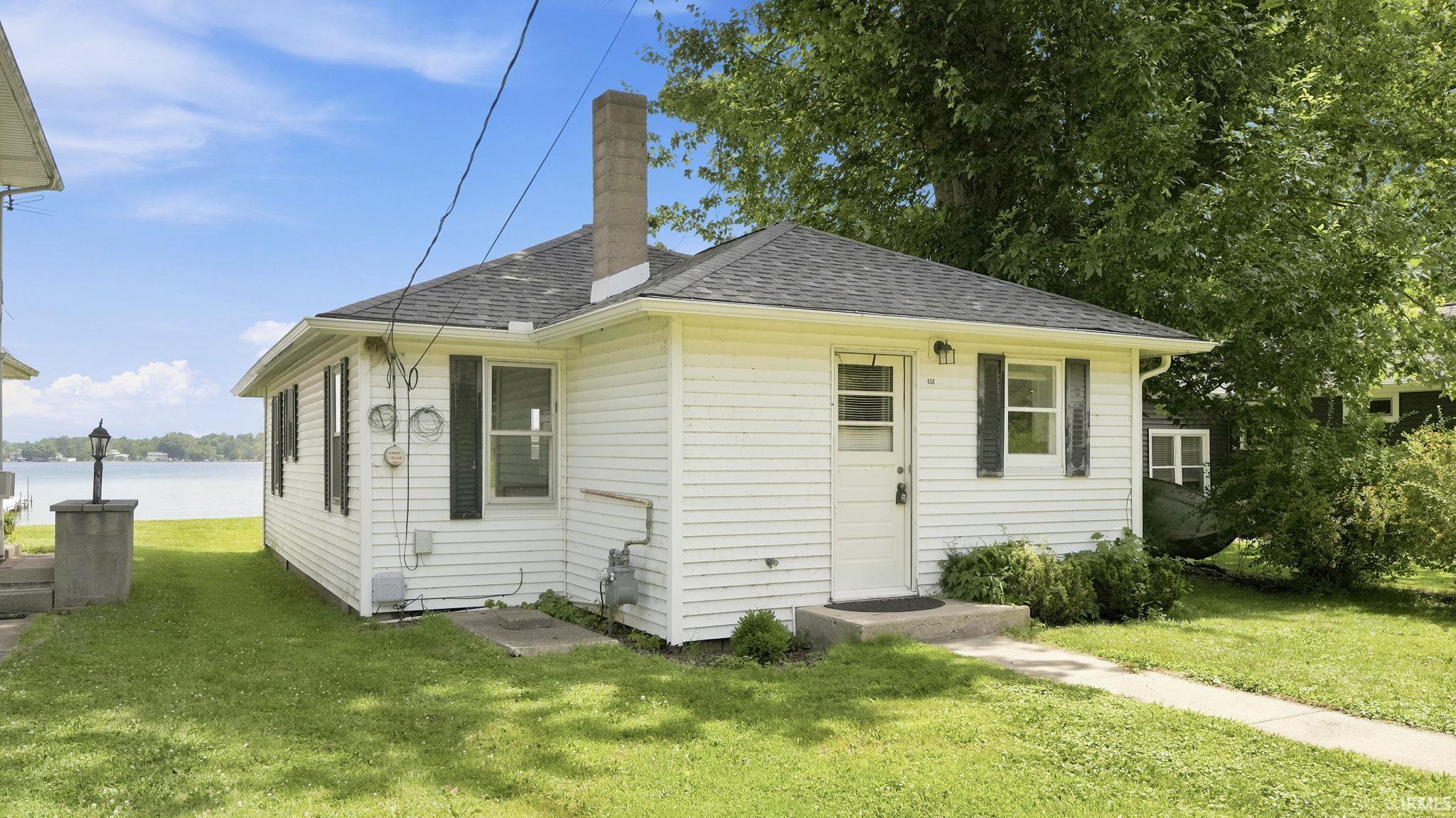 White clapboard siding exterior with a dark shingled roof and a stone chimney