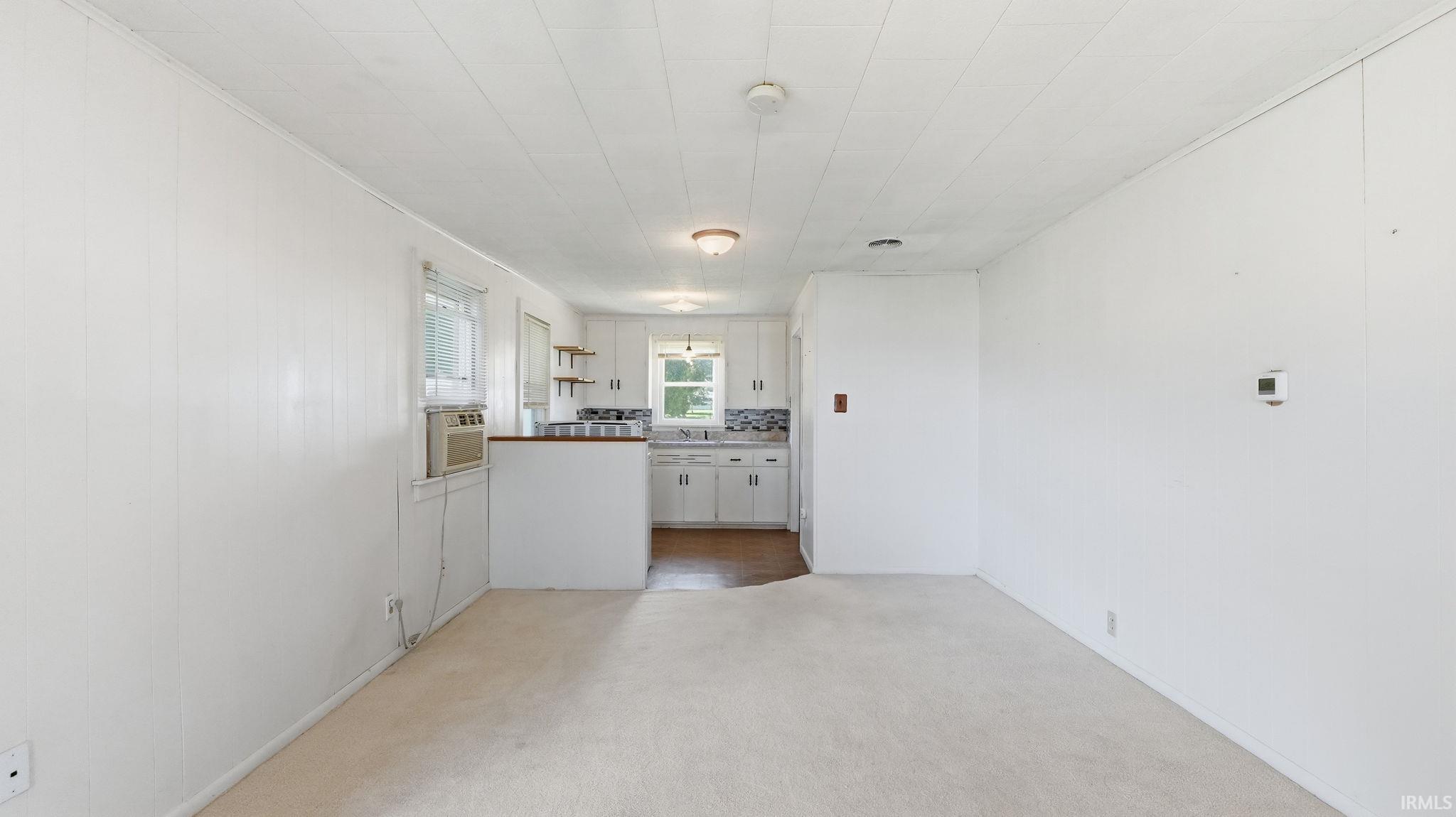 White kitchen cabinetry with open shelving and a mosaic tile backsplash