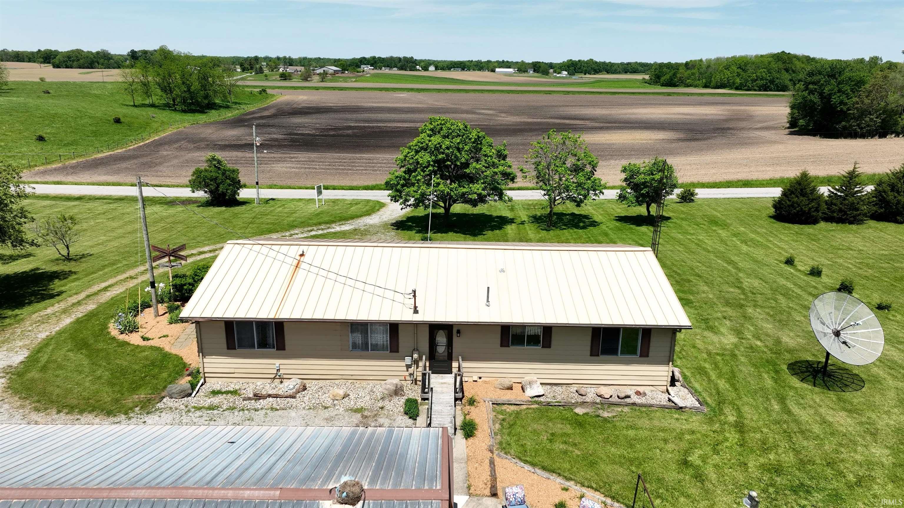 Ranch-style residence featuring a light-colored metal roof and beige siding