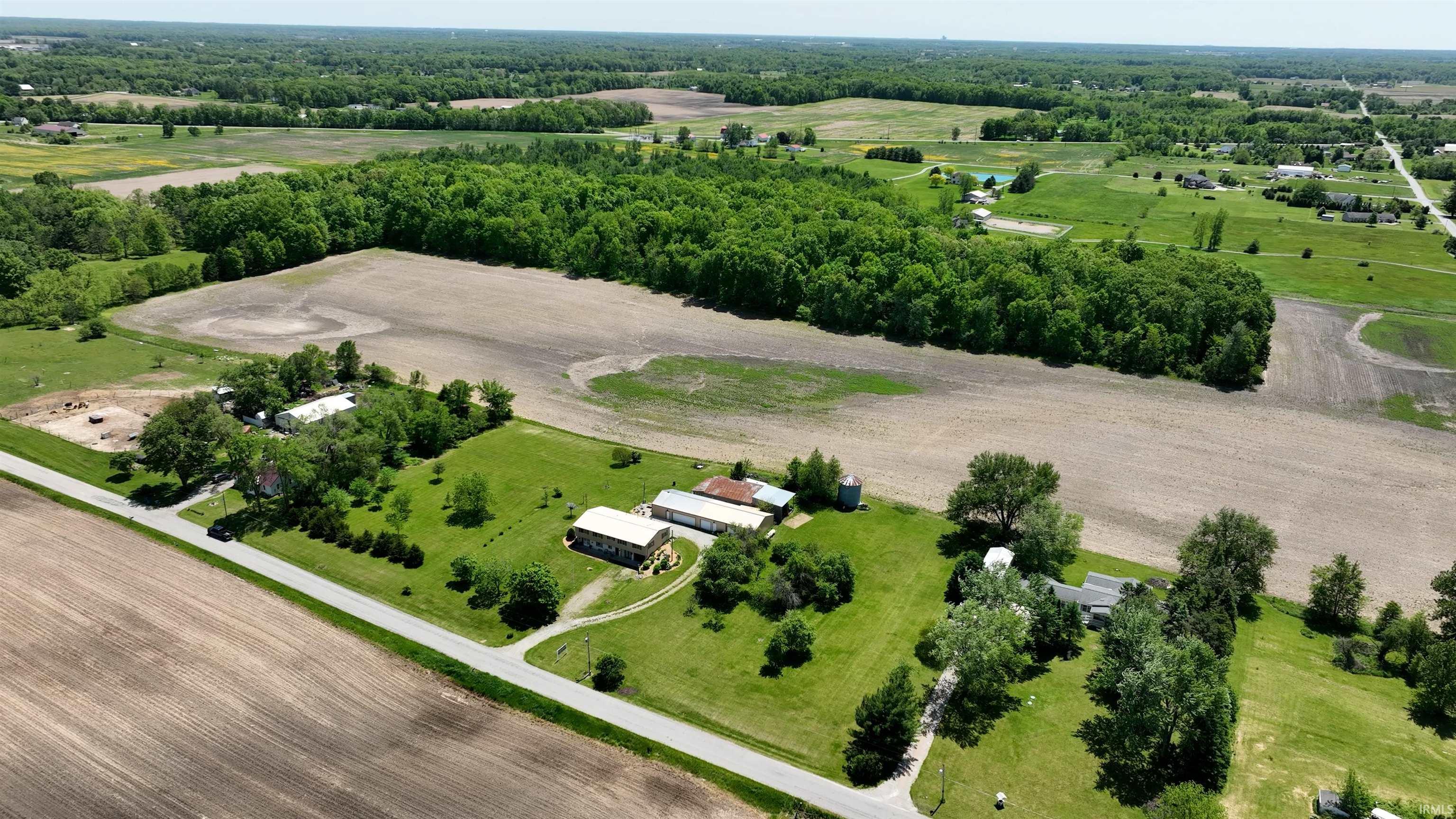 Rural property featuring expansive green lawns, mature trees, and multiple outbuildings