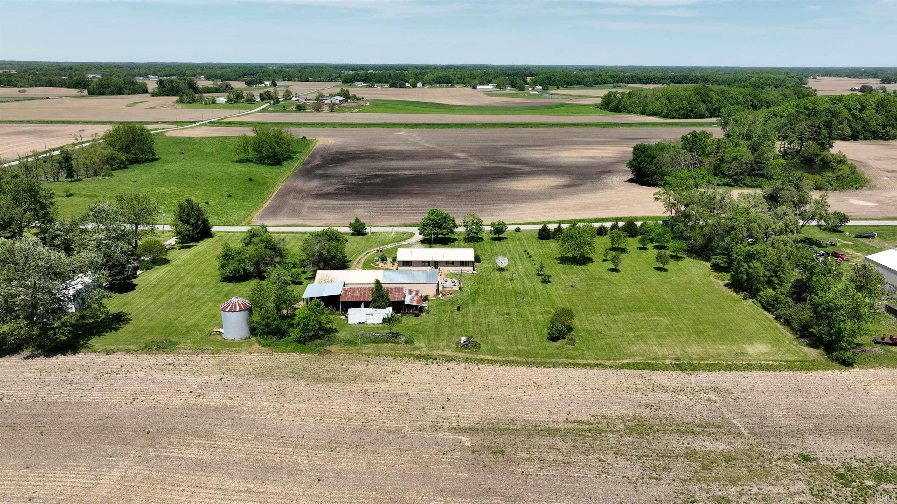 Expansive rural property featuring an established residence, multiple outbuildings, and surrounding agricultural fields