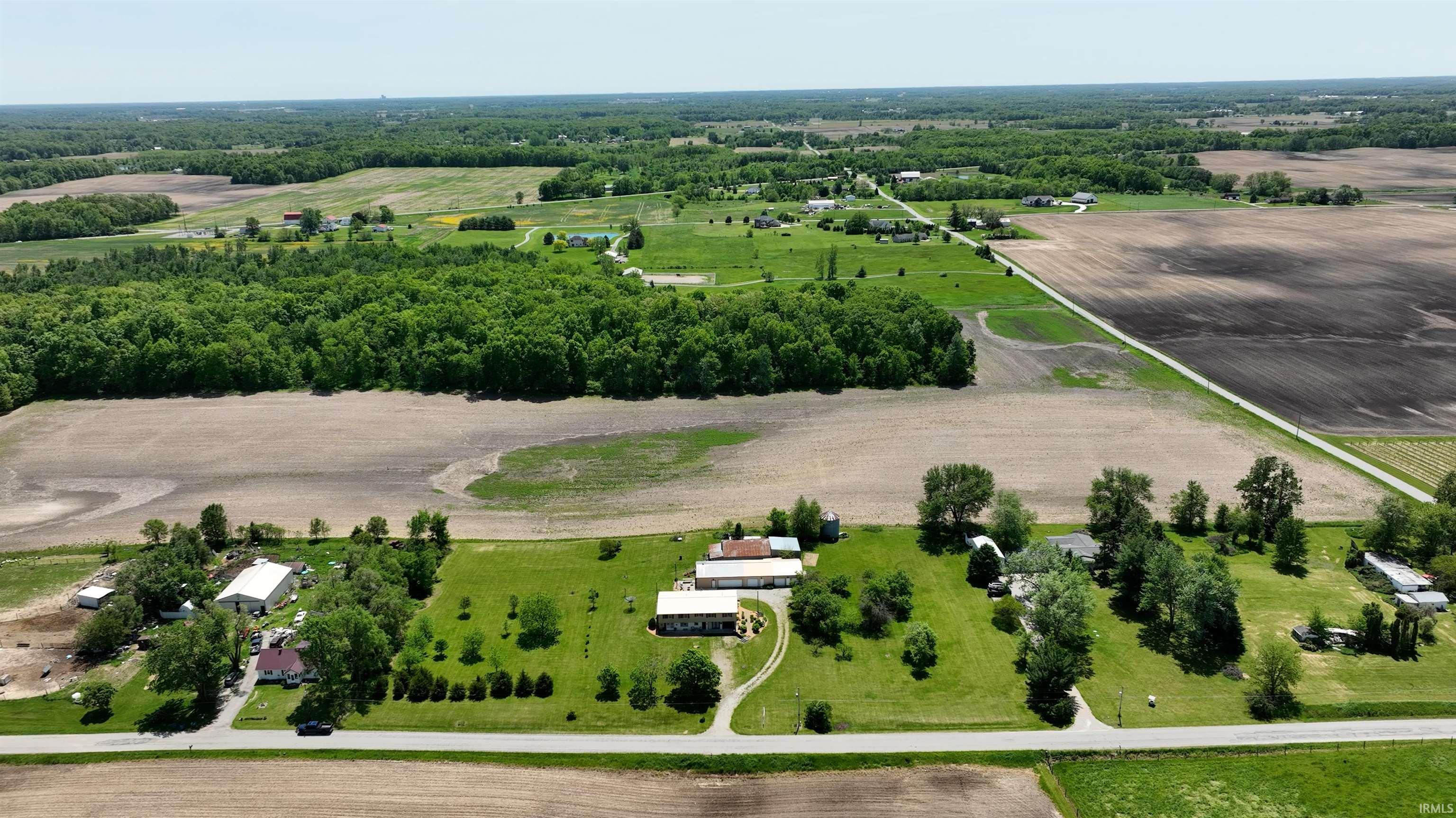 Expansive rural property featuring multiple structures, verdant green lawns, and mature trees
