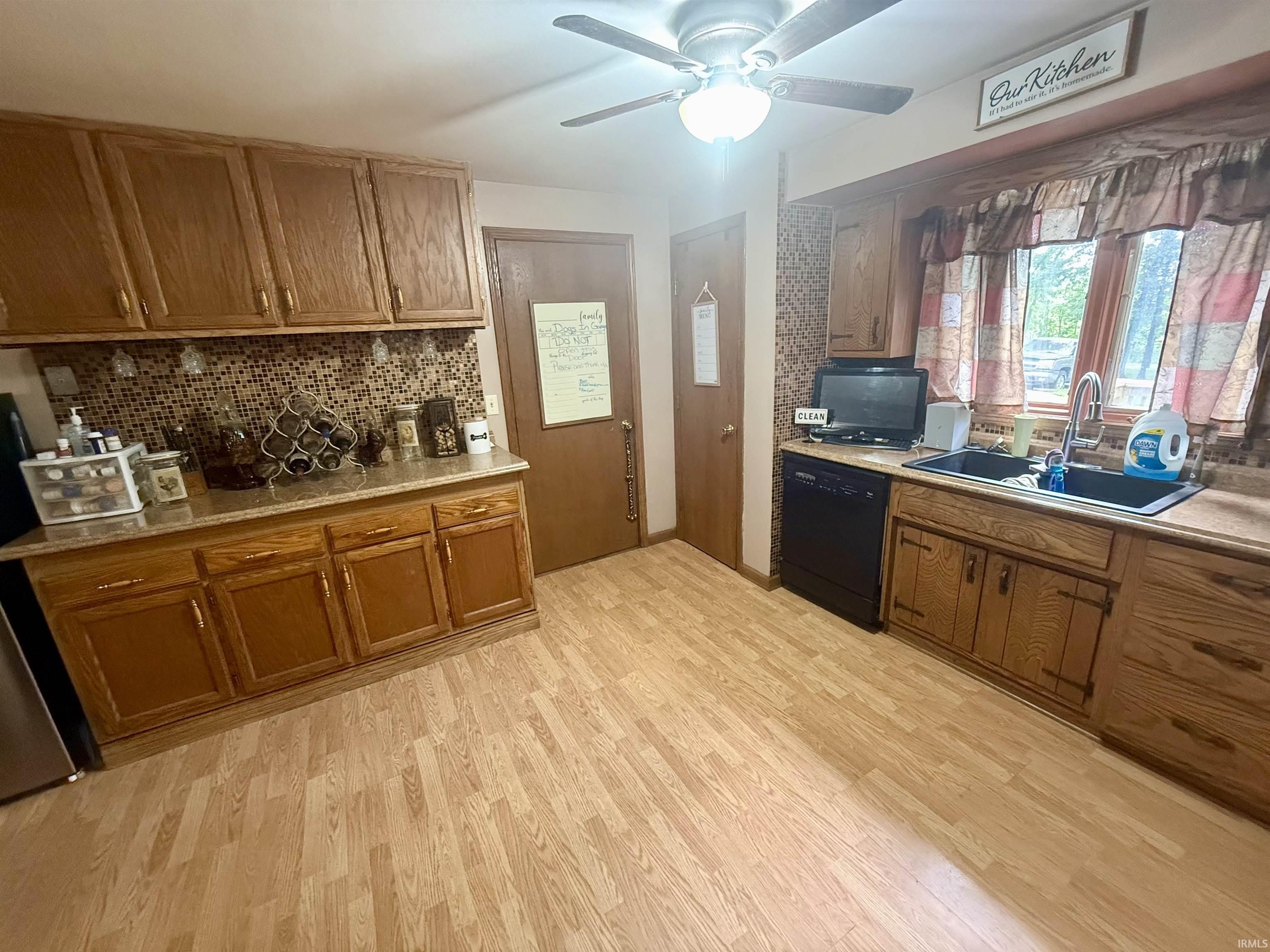 Kitchen featuring wood-finish flooring, oak cabinetry, a tile backsplash, and laminate countertops