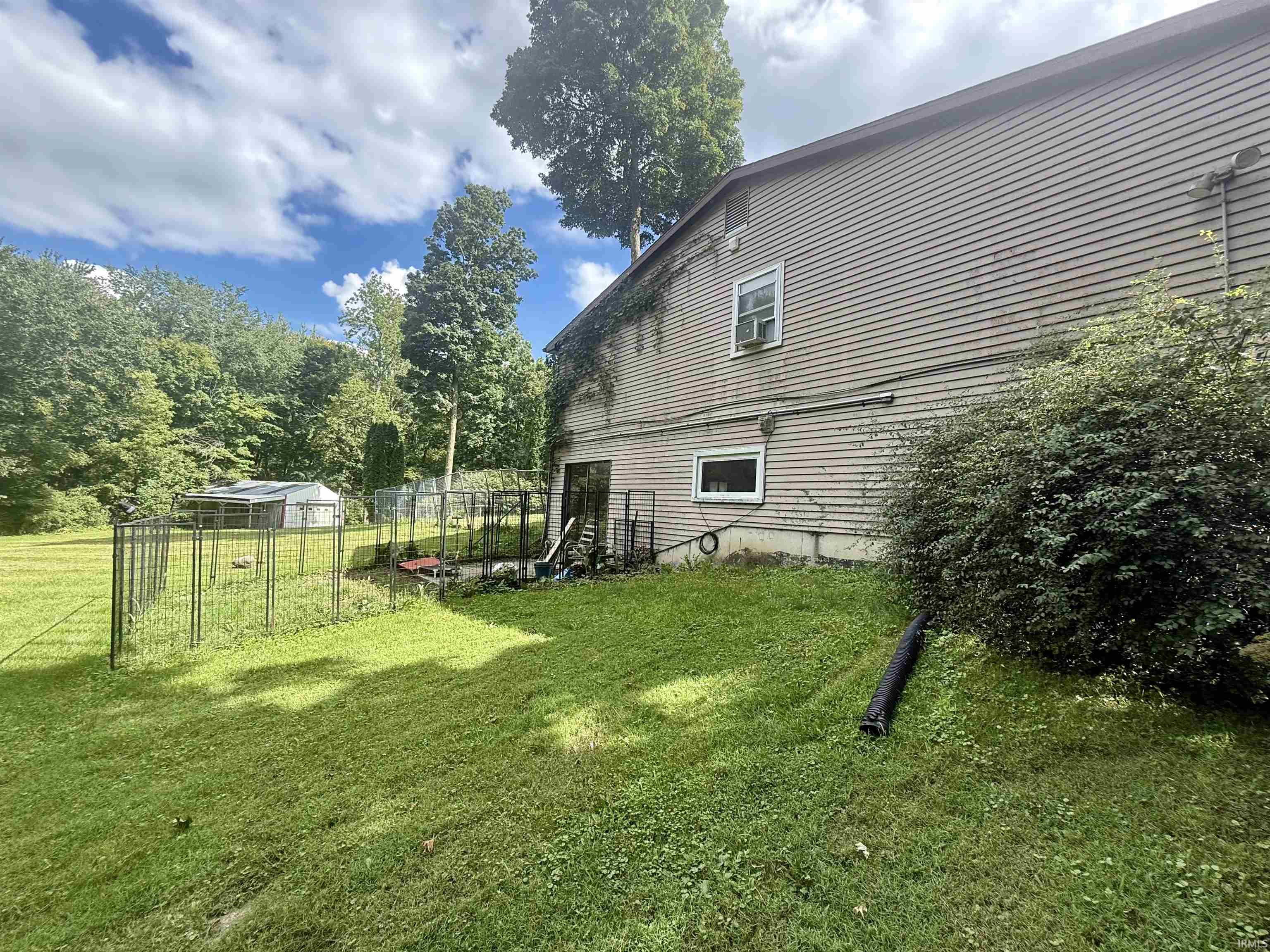 Expansive green lawn with mature trees, fenced area, and a detached shed