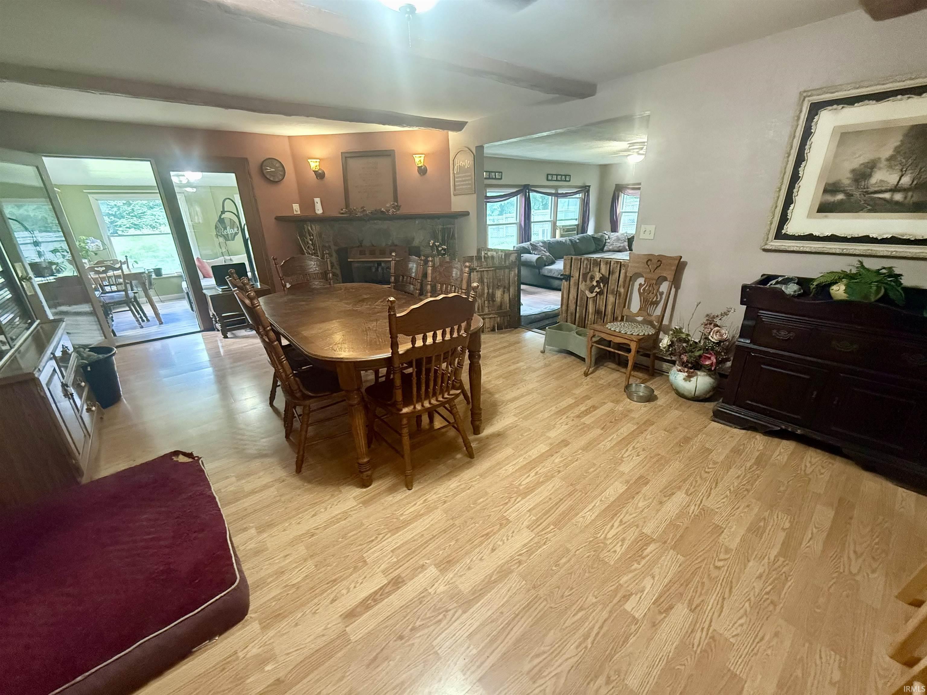 Wood-finish flooring throughout the dining area, stone fireplace, and exposed ceiling beams
