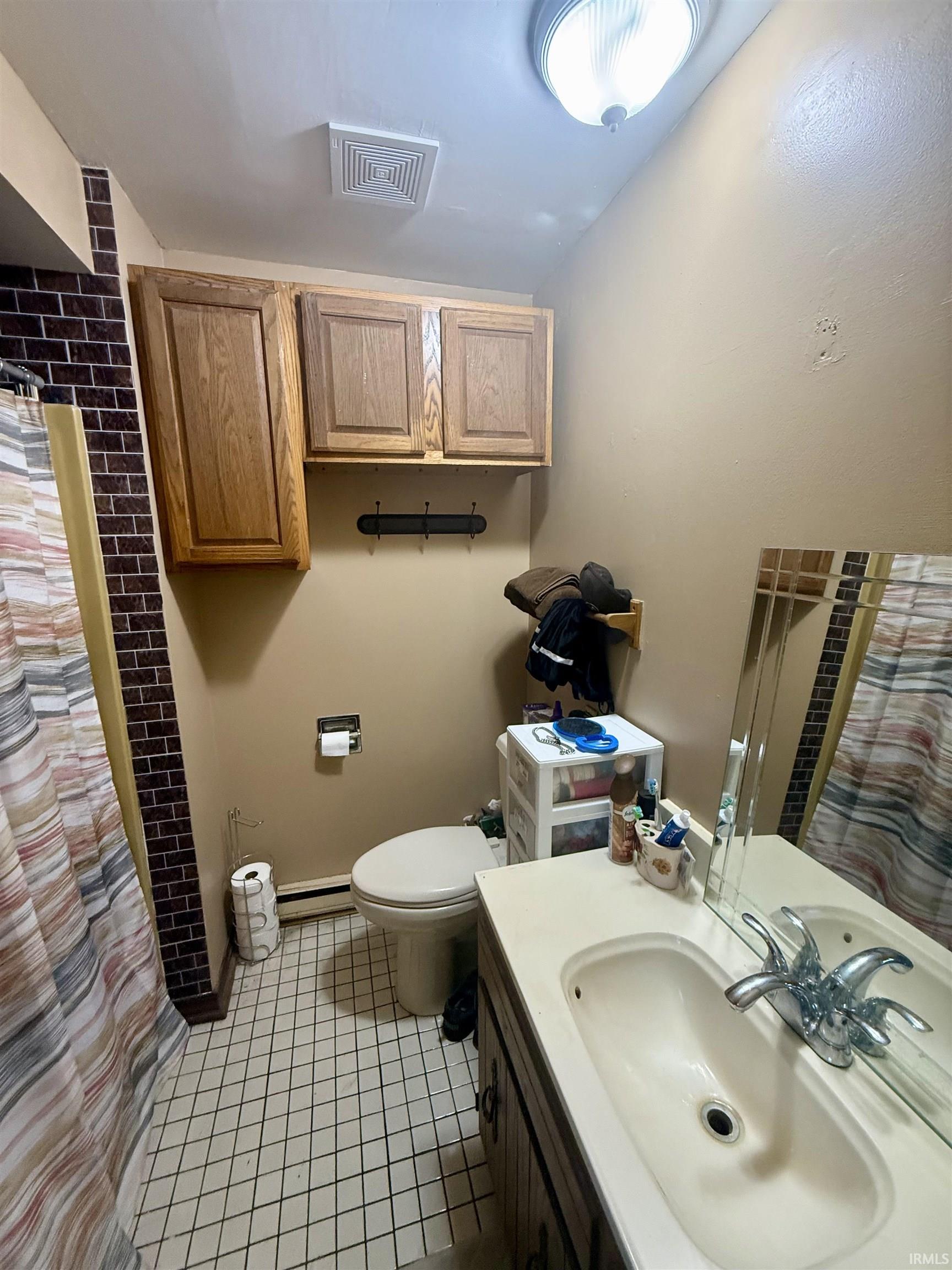 Bathroom featuring wood cabinetry, a vanity with an integrated sink, a built-in mirror, and tiled flooring