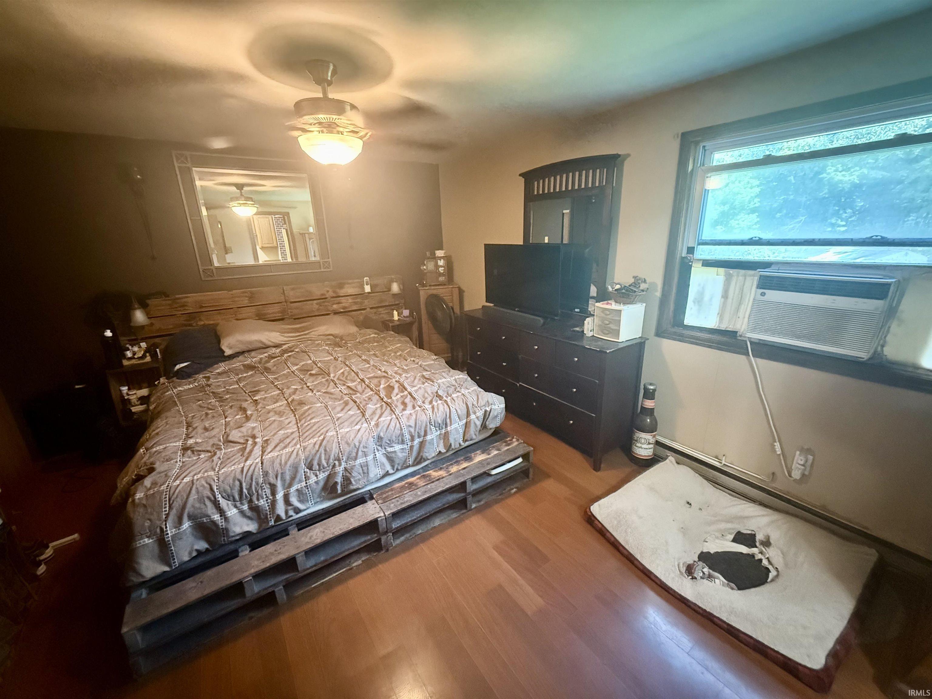 Hardwood flooring with a window AC unit and a ceiling fan with integrated lighting