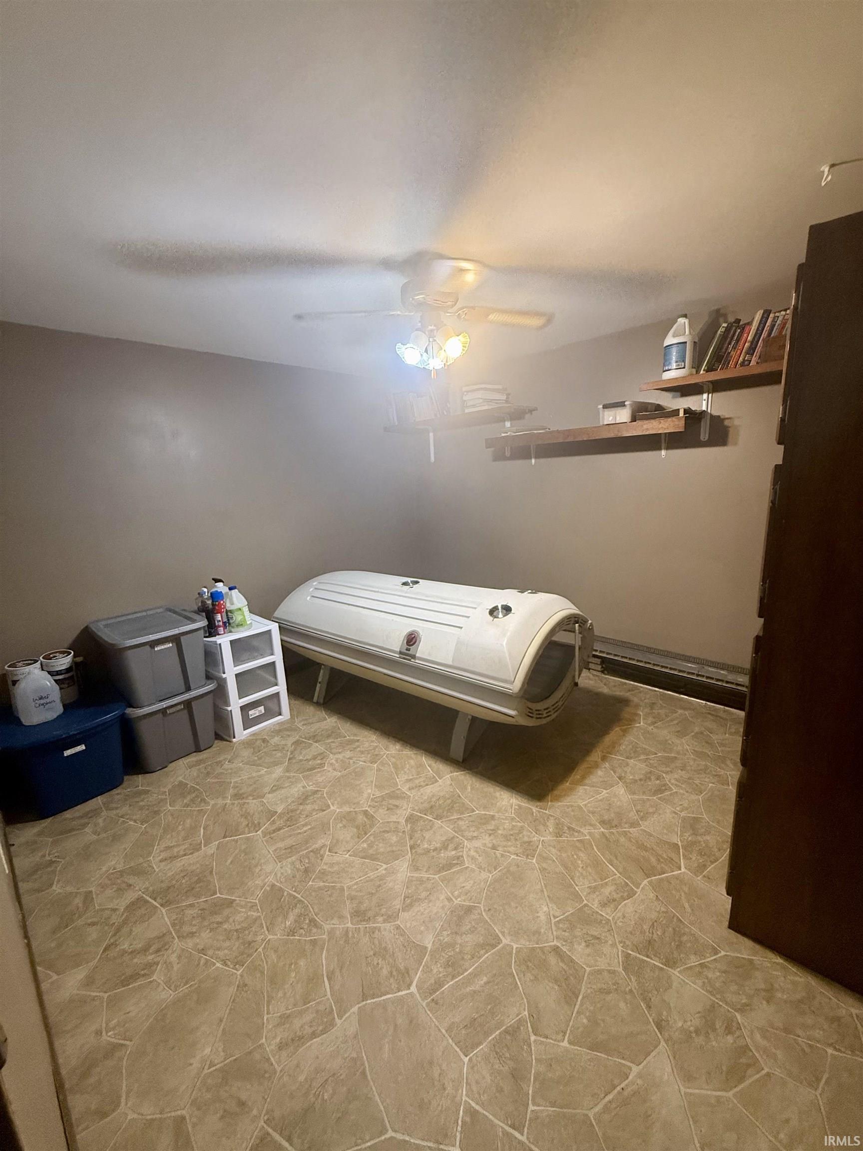 Room featuring neutral wall tones, patterned tile flooring, and a ceiling fan with integrated lighting