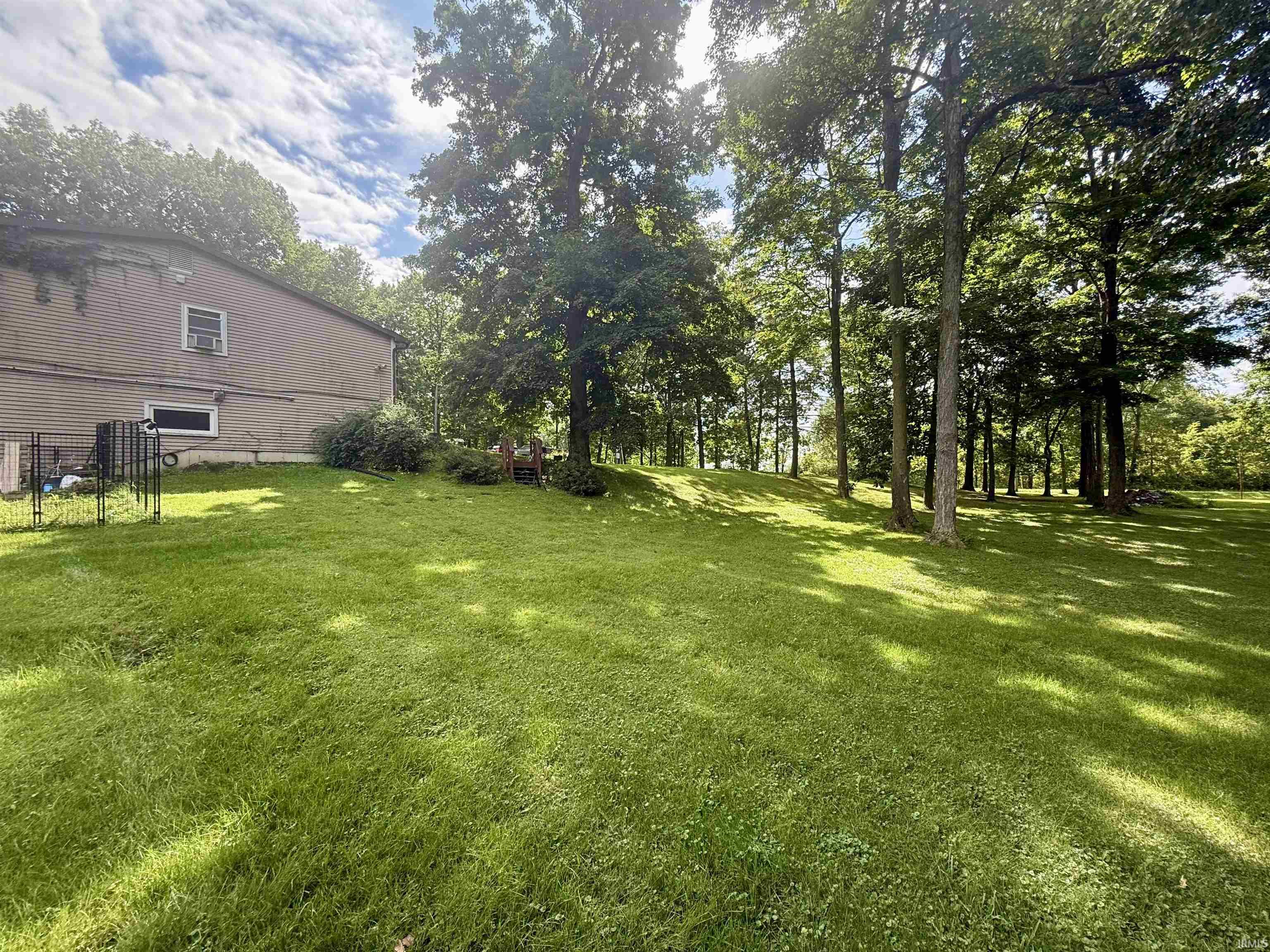 Expansive grassy parcel featuring mature trees providing natural shade