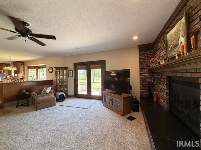 Living area featuring a brick fireplace with a mantle, light-colored carpet, and double French doors opening to an exterior space