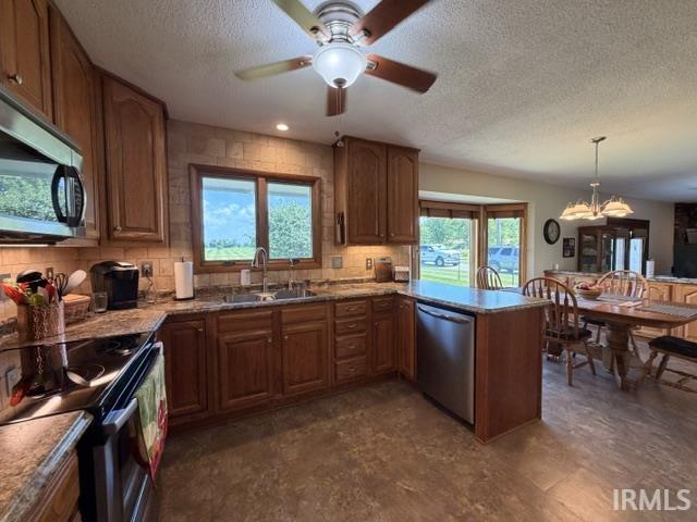 Open-concept kitchen featuring wood cabinetry, stainless steel appliances, a tile backsplash, and composite countertops