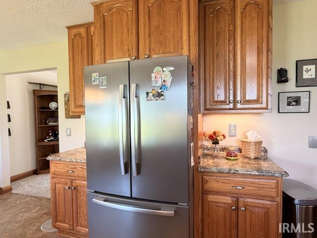Kitchen featuring wood cabinetry, a stainless steel refrigerator, and speckled countertops