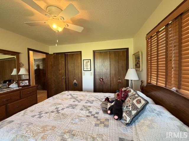 Interior room featuring a ceiling fan with light fixture, wood-finish bi-fold closet doors, and horizontal wood blinds