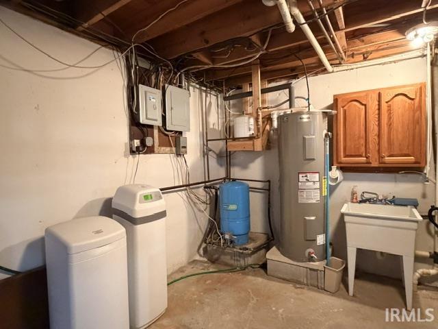 Utility area featuring a water heater, water softener system, utility sink, and electrical panels