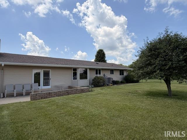 Expansive rear yard featuring a paved patio, a built-in stone retaining wall, and mature trees