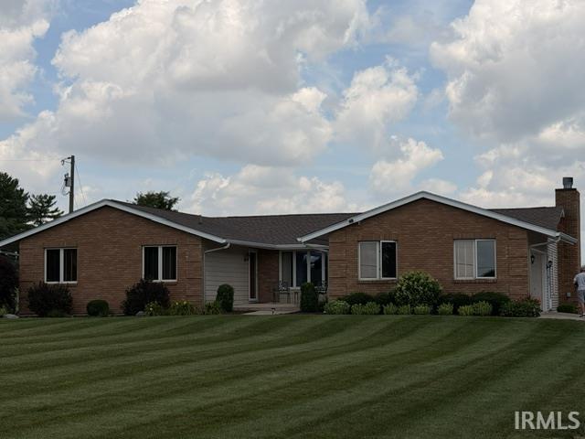 Brick exterior ranch-style residence featuring a prominent front lawn, established landscaping, and a side chimney