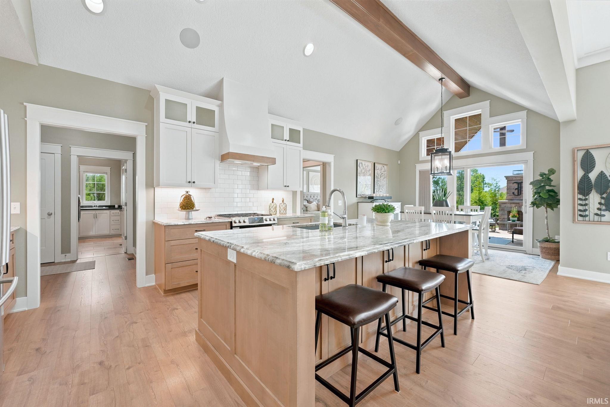Kitchen featuring a central island with a light-toned countertop, wood-finish flooring, white upper cabinetry, and a subway tile backsplash